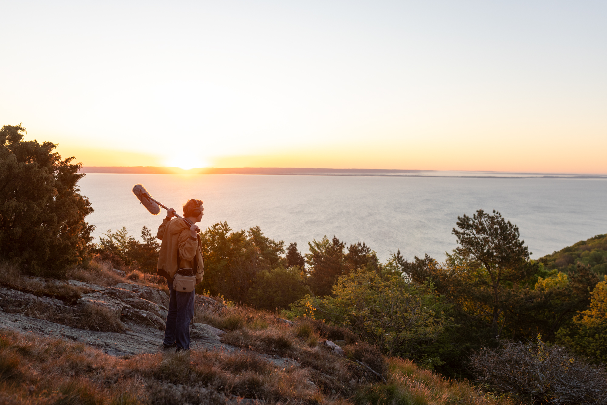 A man standing on top of a hill holding a microphone.