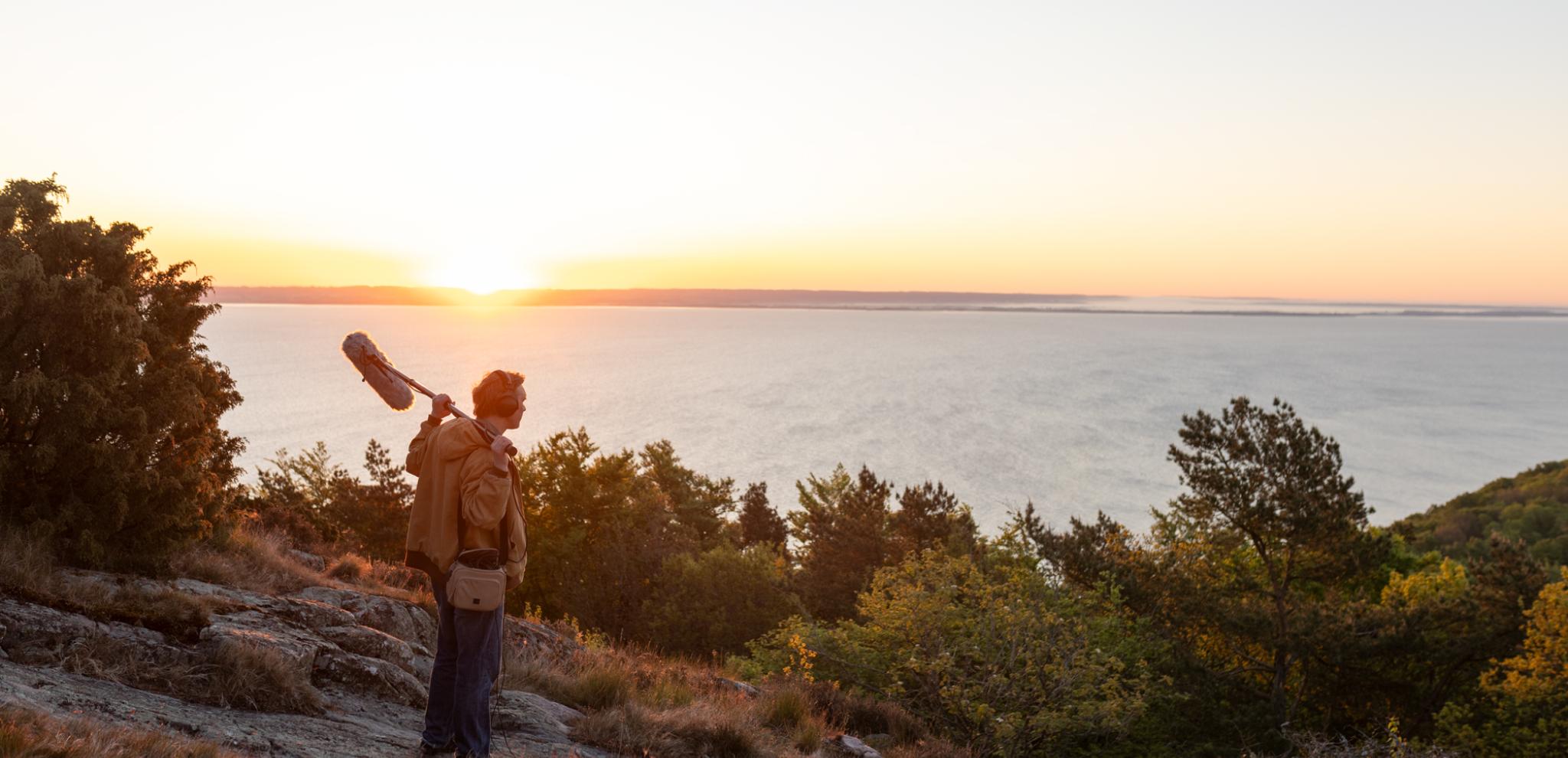 A man standing on top of a hill holding a microphone.