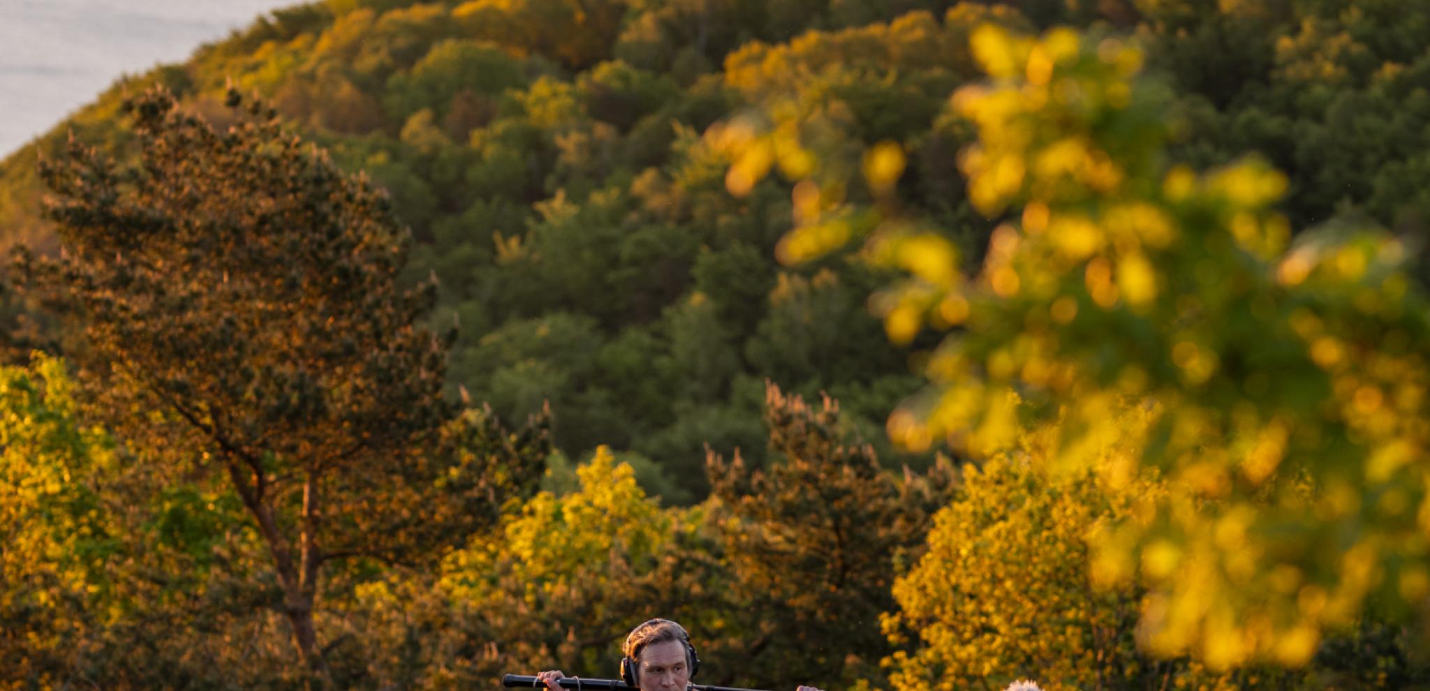 A man standing on top of a lush green hillside.