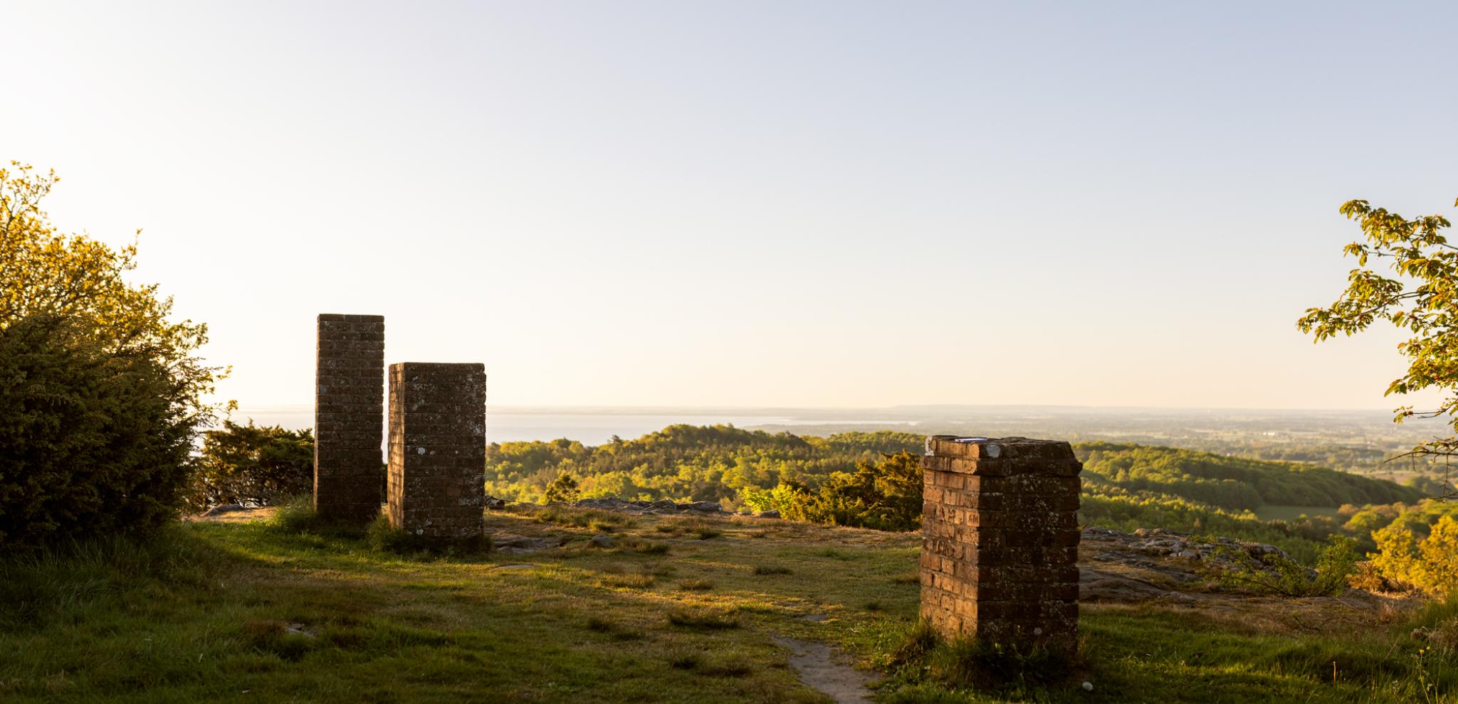 A couple of stone pillars sitting on top of a lush green hill.