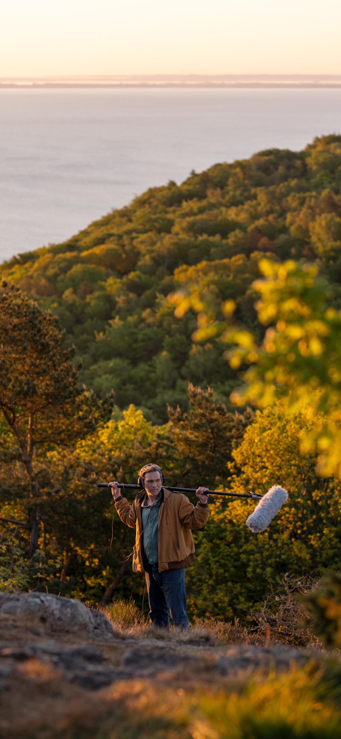 A man standing on top of a lush green hillside.