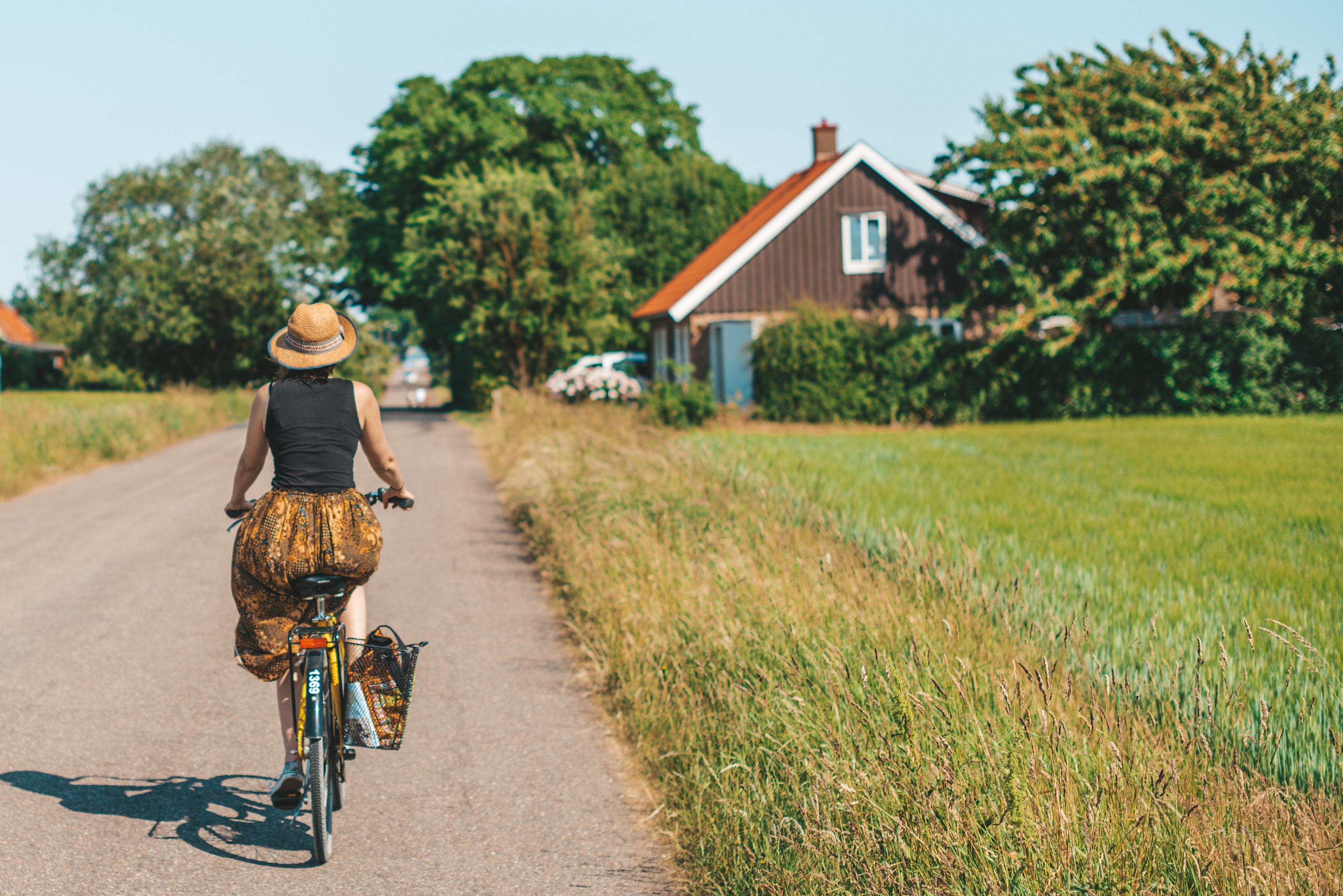 Kvinna som cyklar på en landsväg i Ven en vacker sommardag