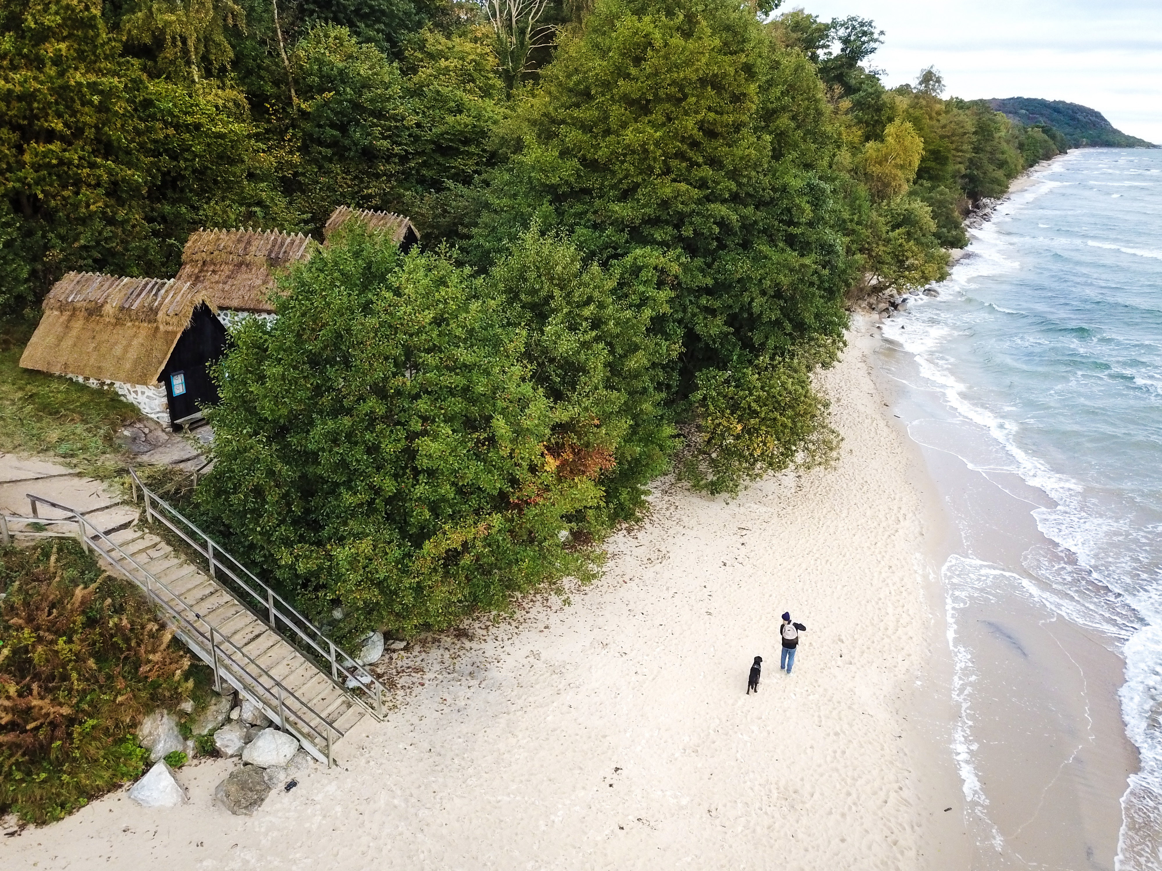 Man and dog walking on a white beach at Knäbäckshusen