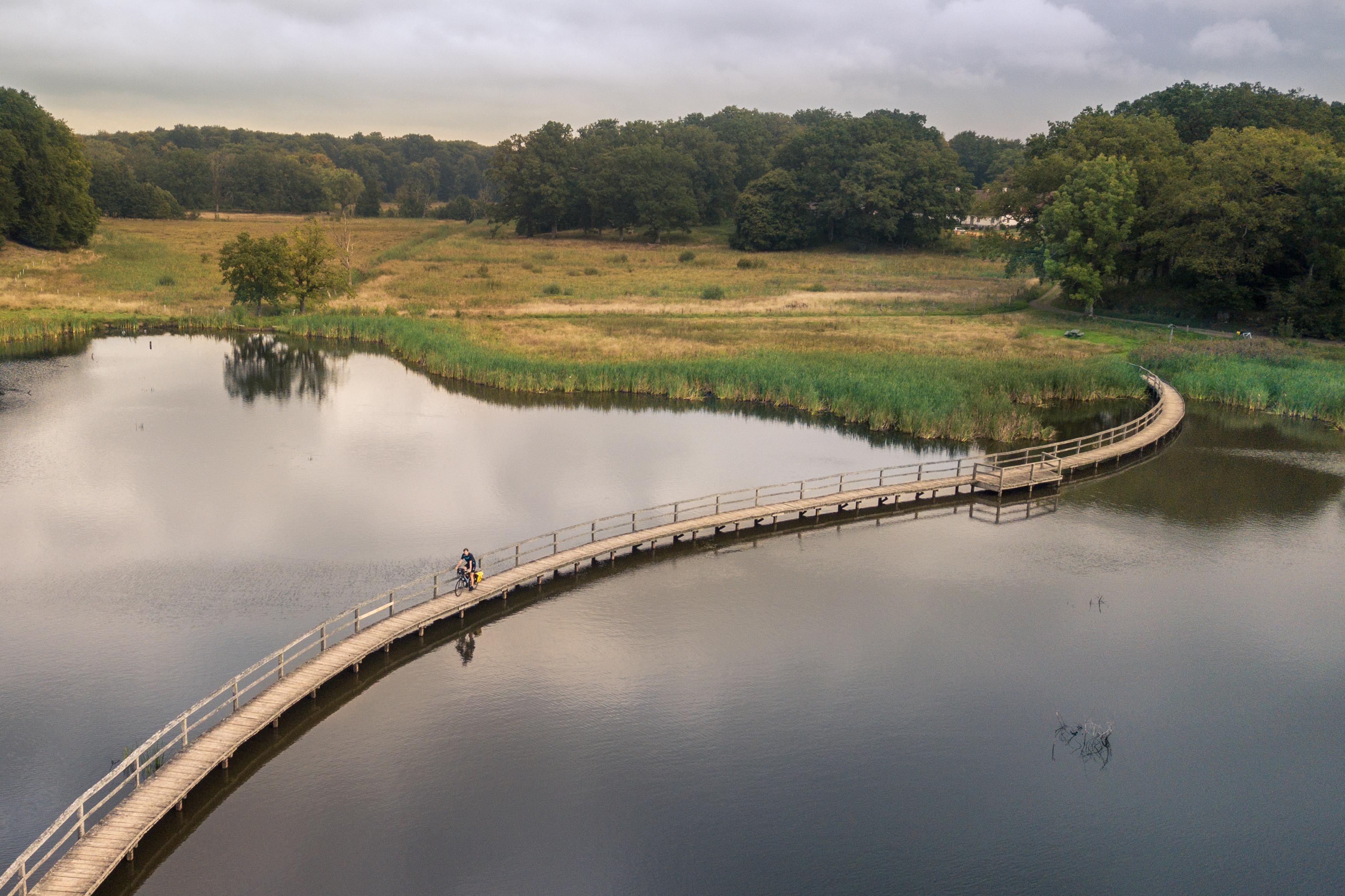 cyclist bikes on a long bridge across water