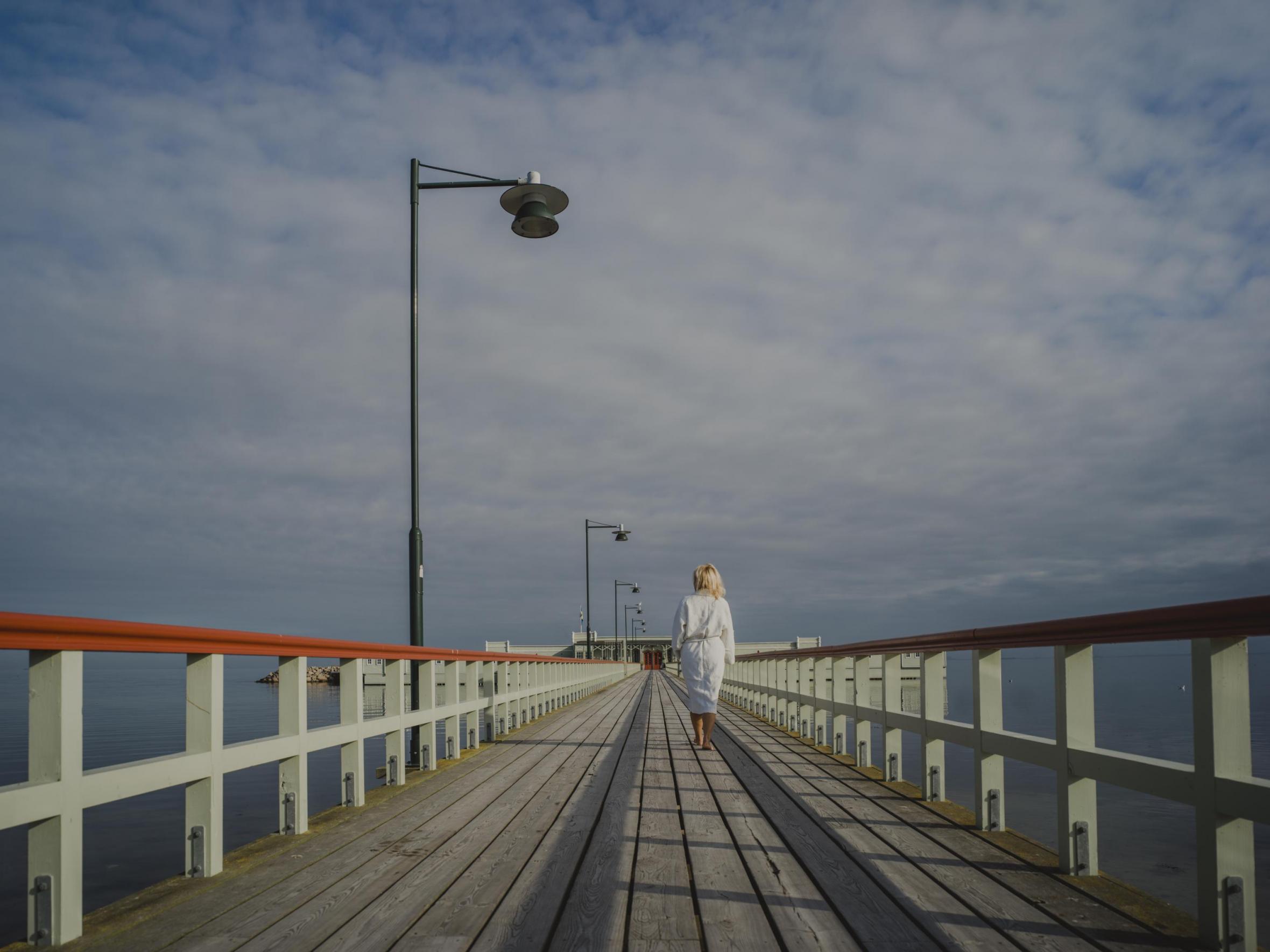 A woman walking towards Ribersborg's cold bath house on a summer day