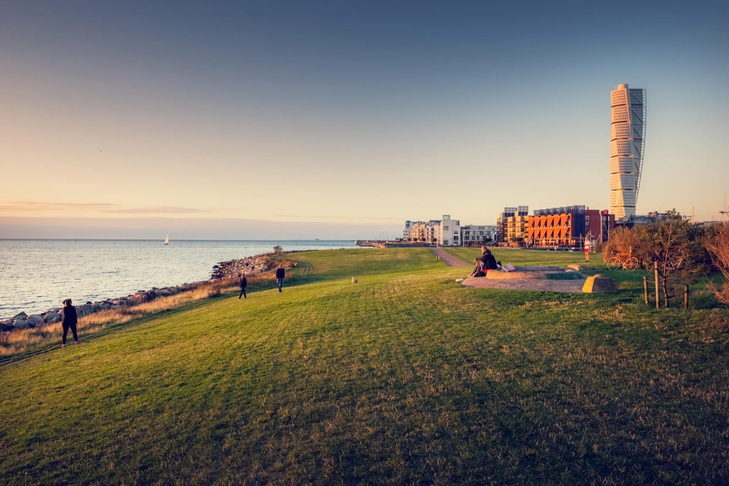 Människor njuter av en vacker solnedgång vid strandpromenaden i Västra hamnen 