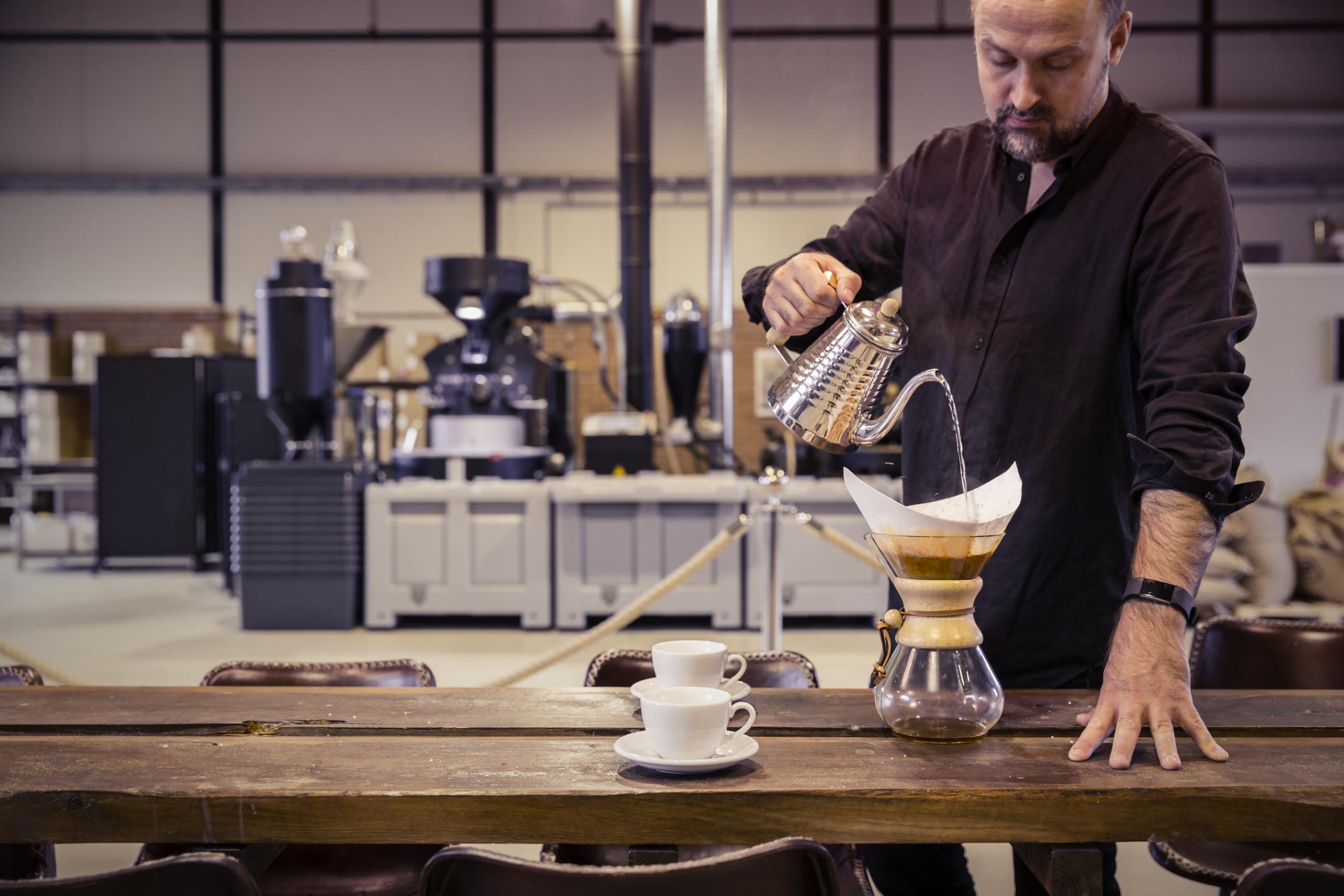 Man pouring coffee in decanter on wooden table