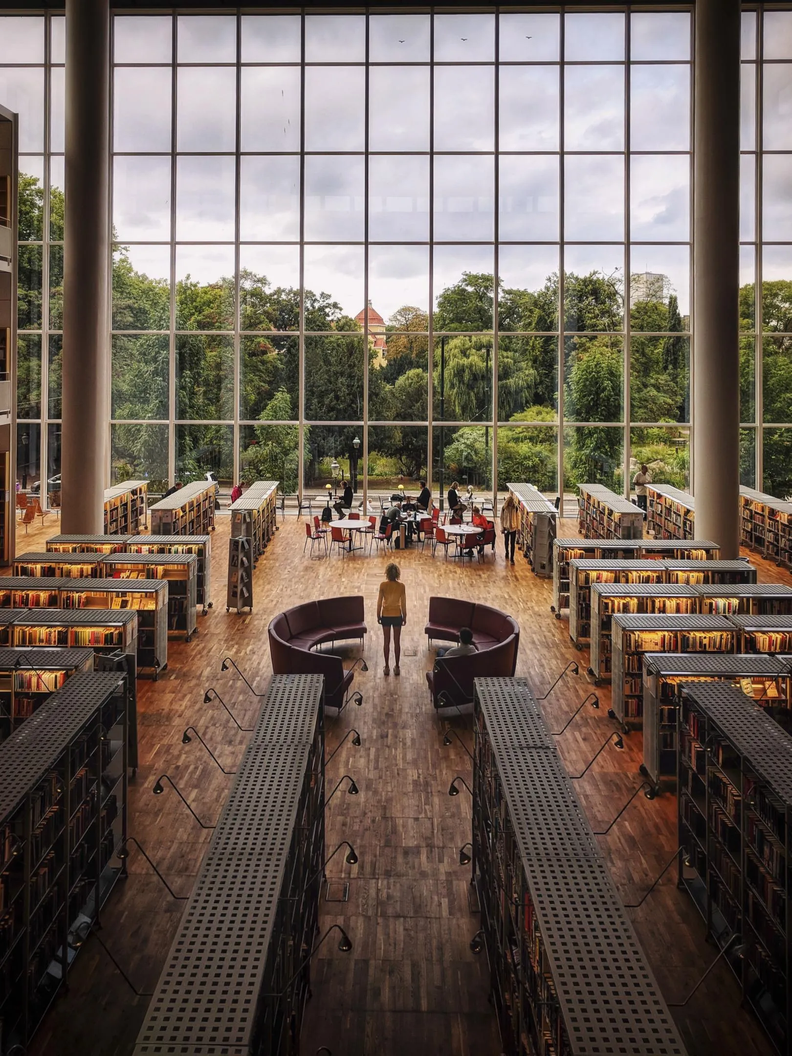 Der Blick vom Inneren der Malmöer Stadtbibliothek auf einen üppigen Park mit grünen Bäumen.