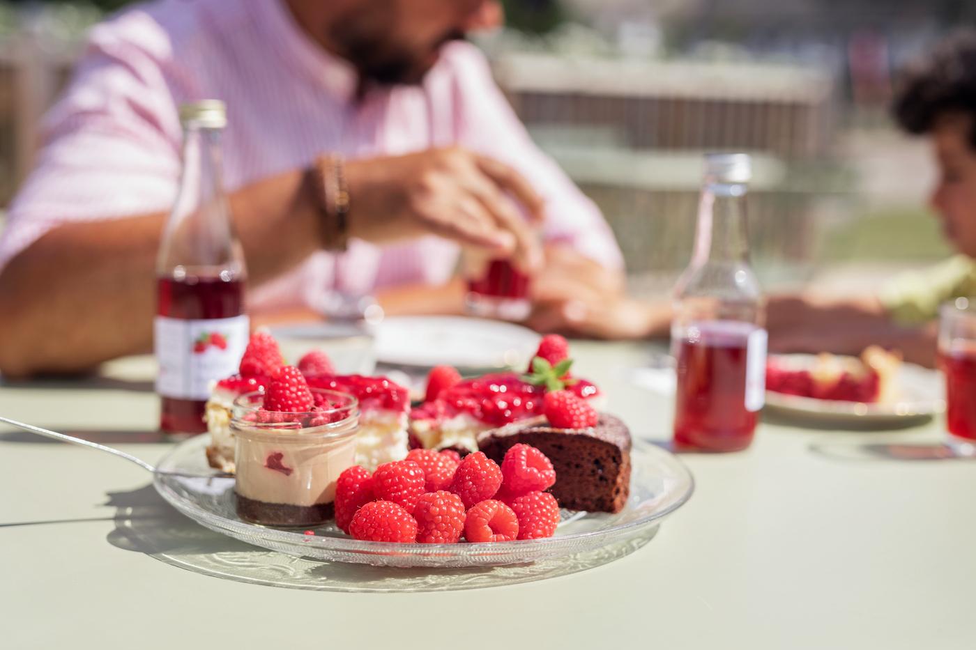 Ett fat med hallontårta och en man som fikar i bakgrunden