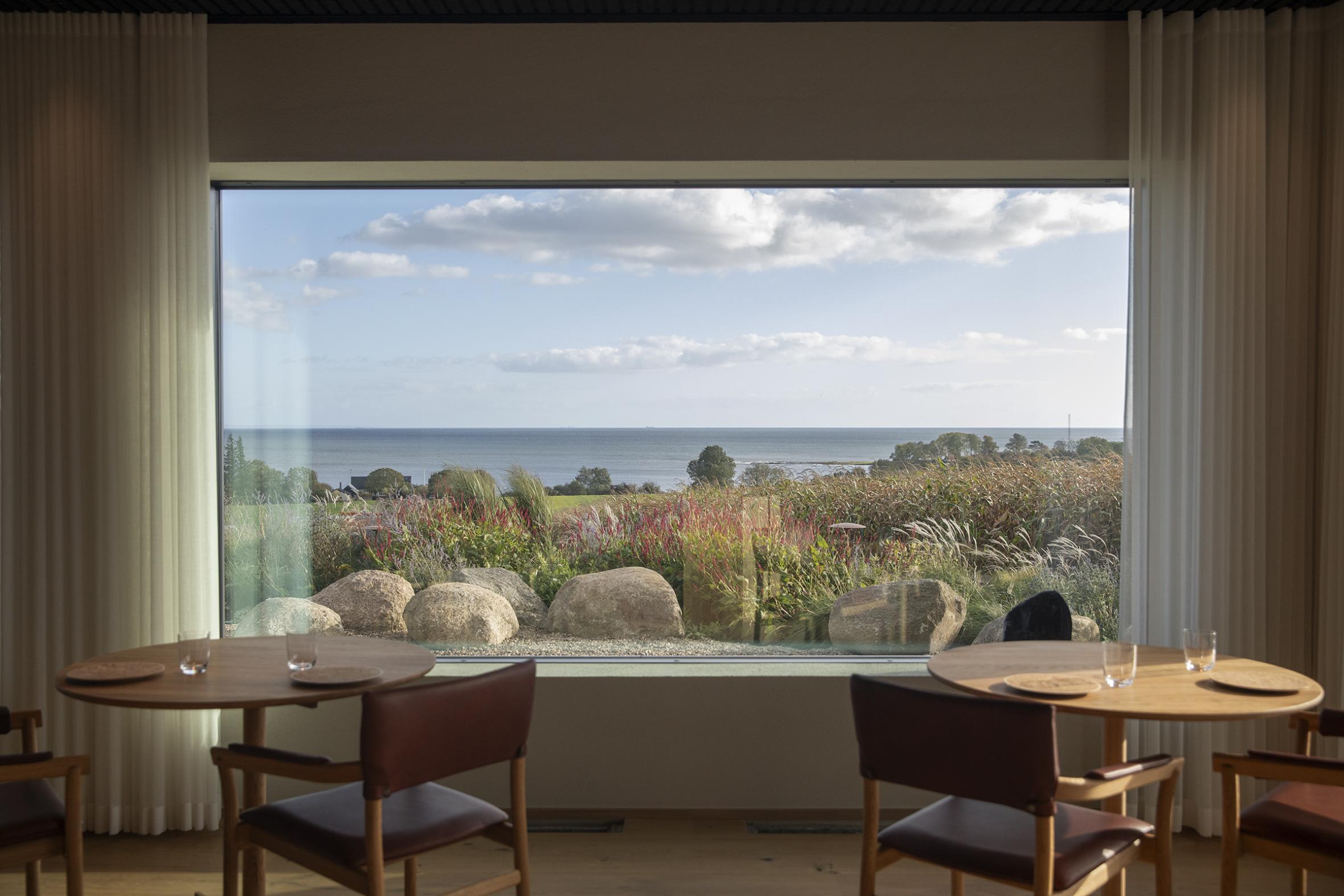 Elegant restaurant interior with two minimalist tables overlooking a breathtaking scenic view