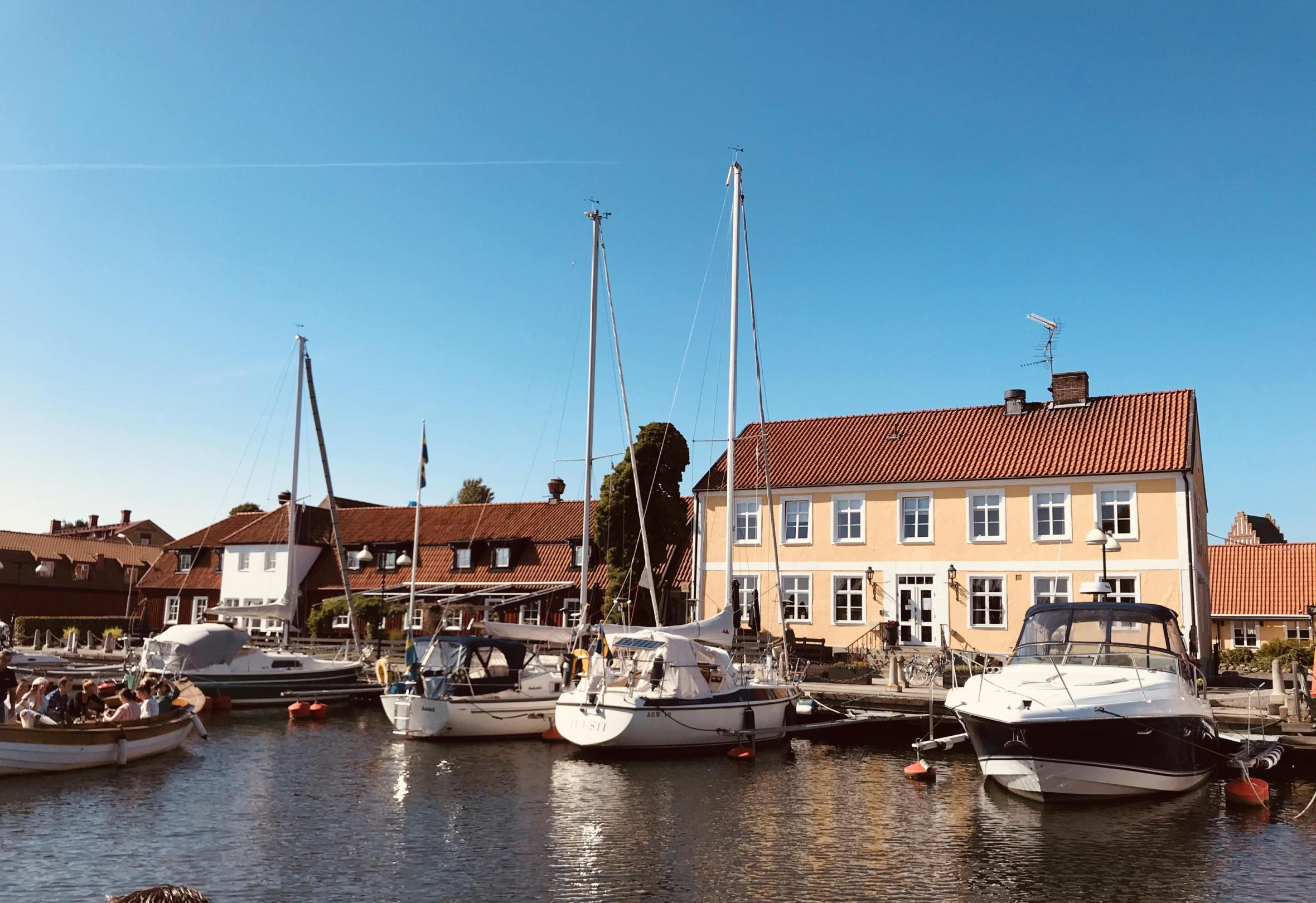 Sailing boat harbor in a canal with a light yellow large house in the background