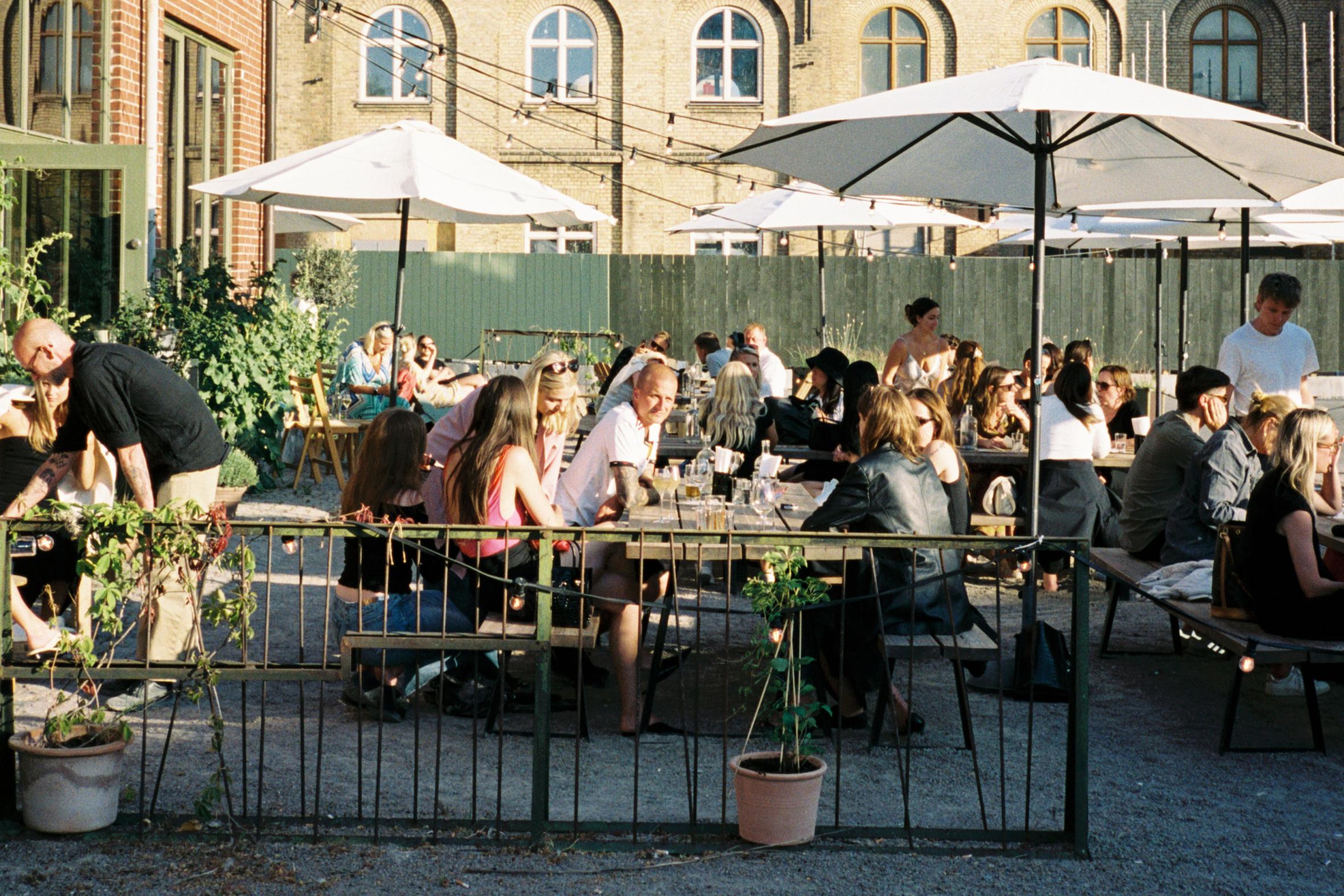 Intimate outdoor restaurant terrace with parasols providing shade on sunny summer day