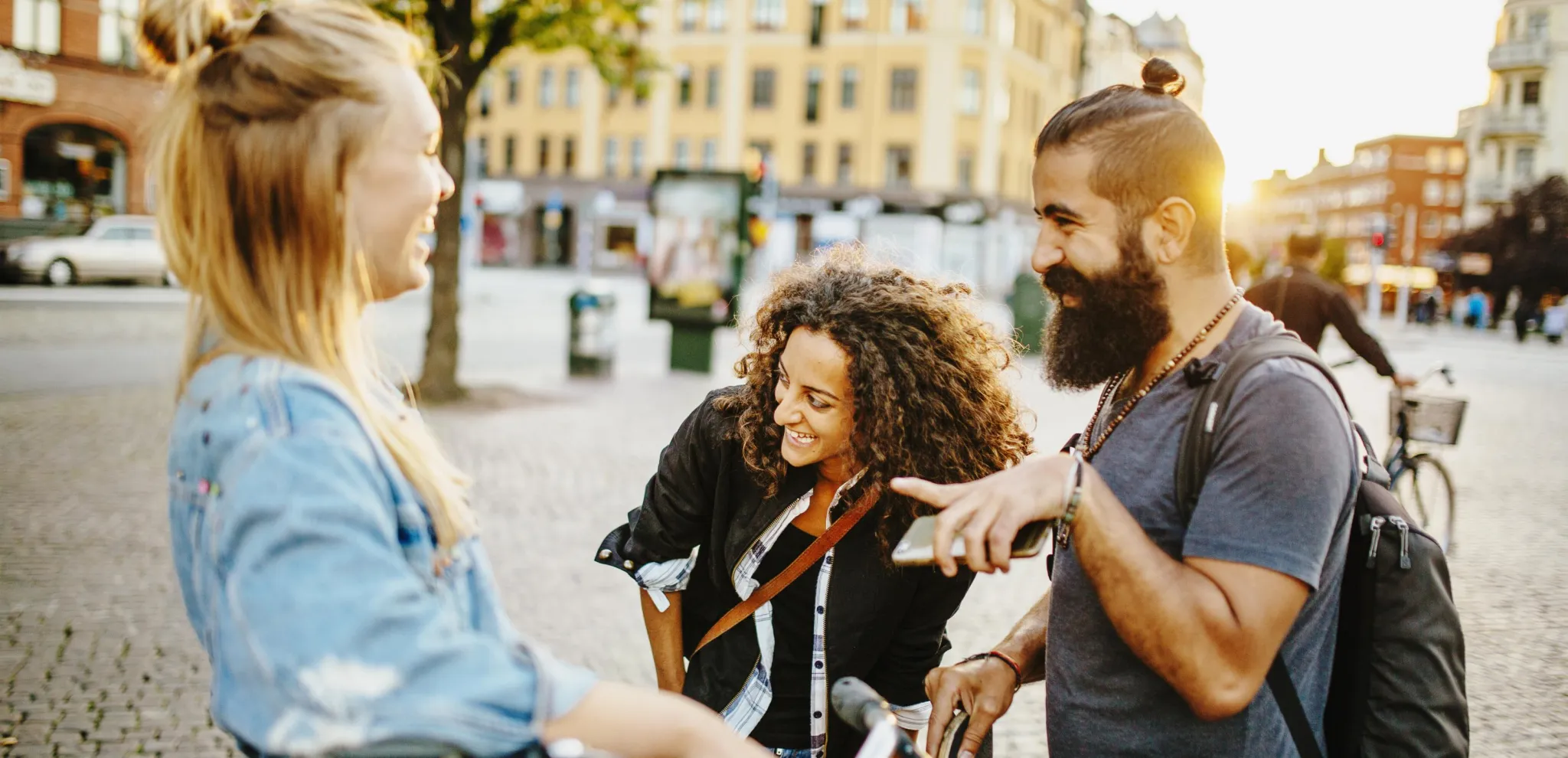 Drei Freunde reden und lachen auf dem Platz Möllevångstorget in Malmö.