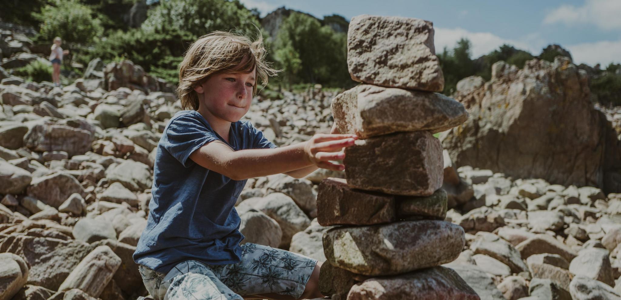 A child stacking stones in Summer in Hovs Hallar 