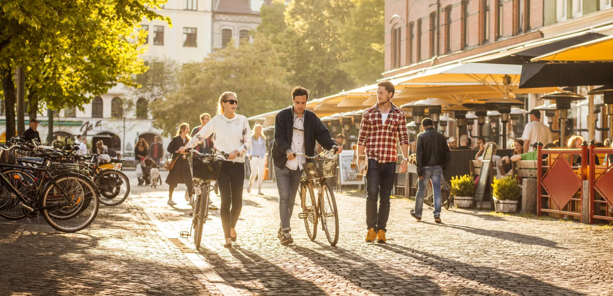  People walking with bikes in the summer at Möllvången's square in Malmö