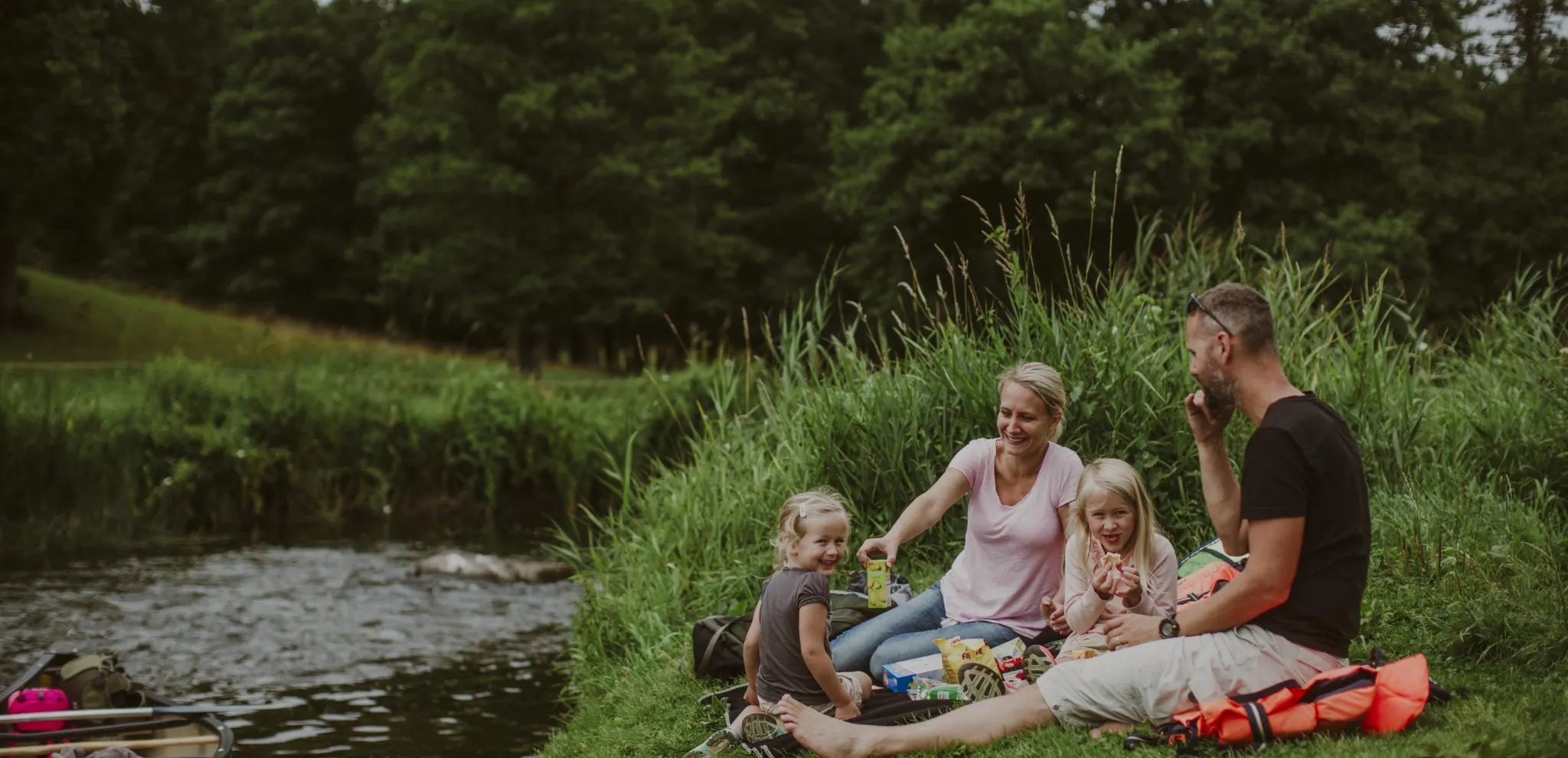 Family enjoy a picnic by the riverbank at Rönne å