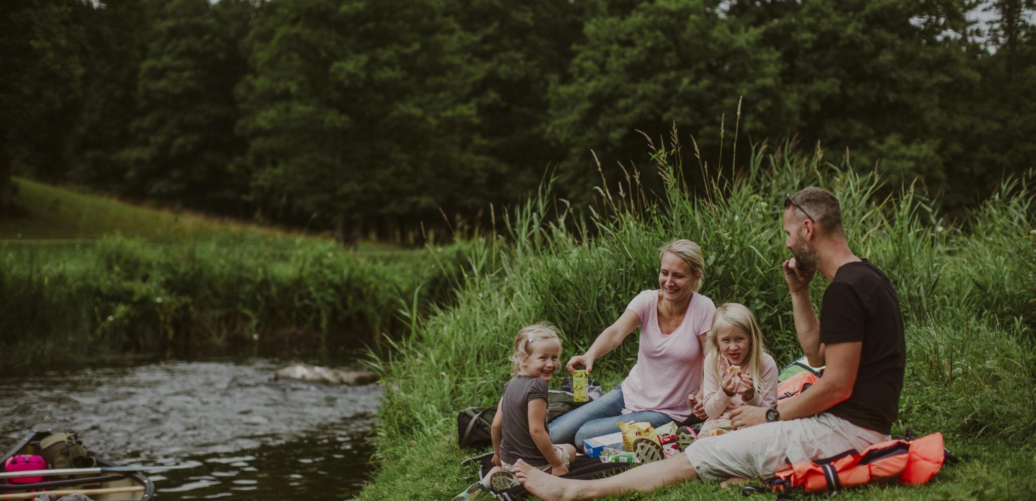 Family enjoy a picnic by the riverbank at Rönne å