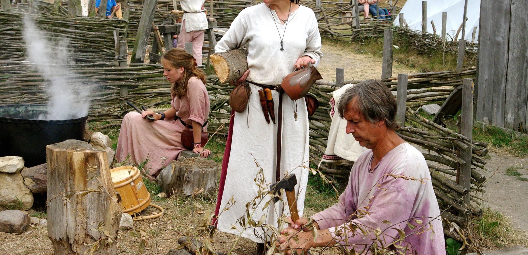 Als Wikinger verkleidete Darsteller im Freilichtmuseum Foteviken über verschiedene Handwerksformen aus.