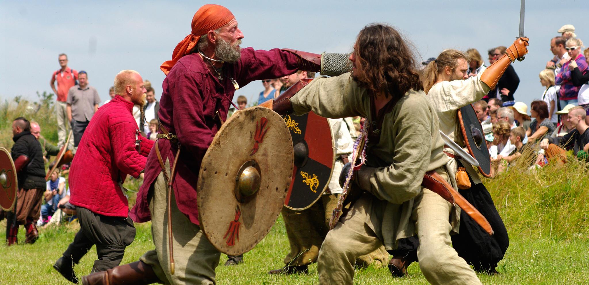 Vikingar med svärd och sköldar rekonstruerar en vikingastrid