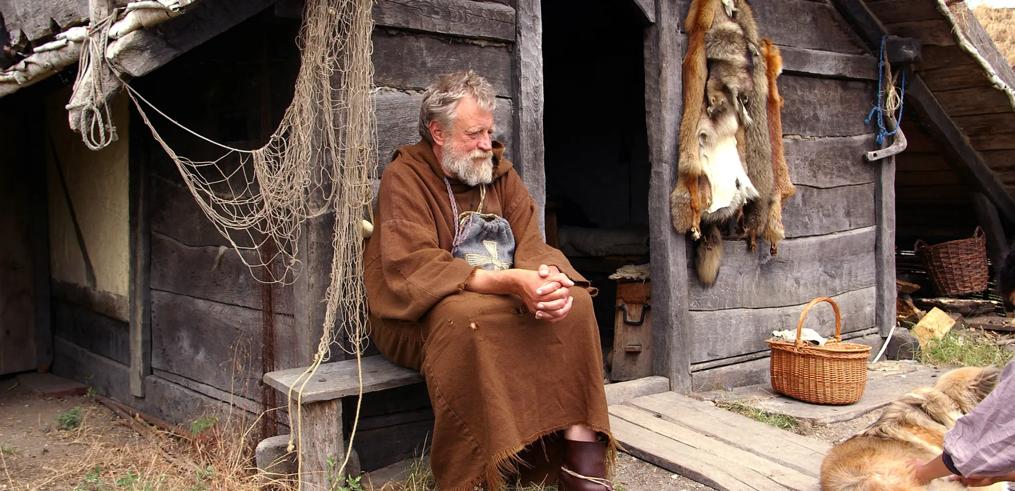 Viking sitter utanför ett hus på Foteviken museum
