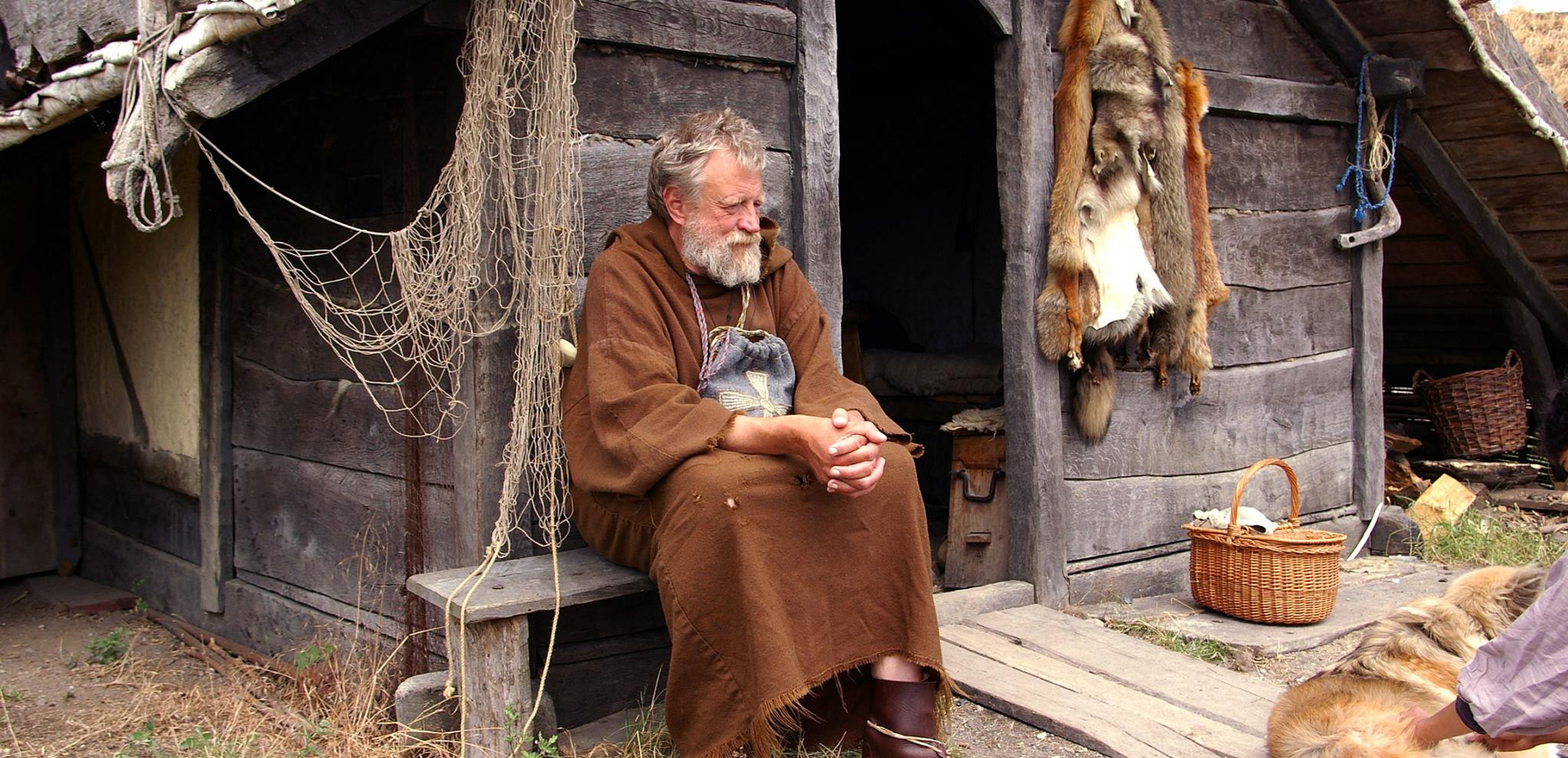A viking sitting outside a house at Fotevikens viking town 