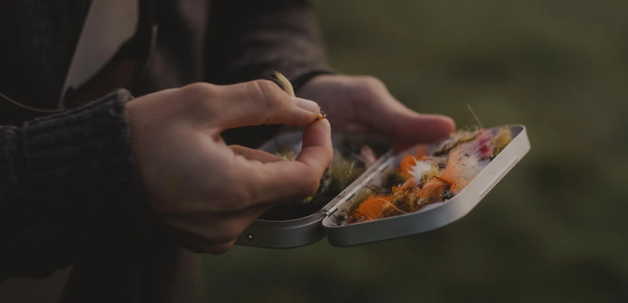 Hands holding a small metal case with fishing baits