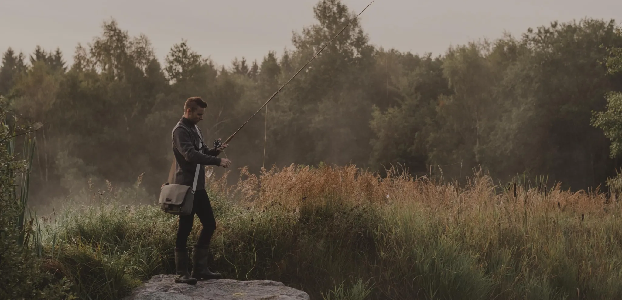 Man fishing a foggy morning with the forest in the background