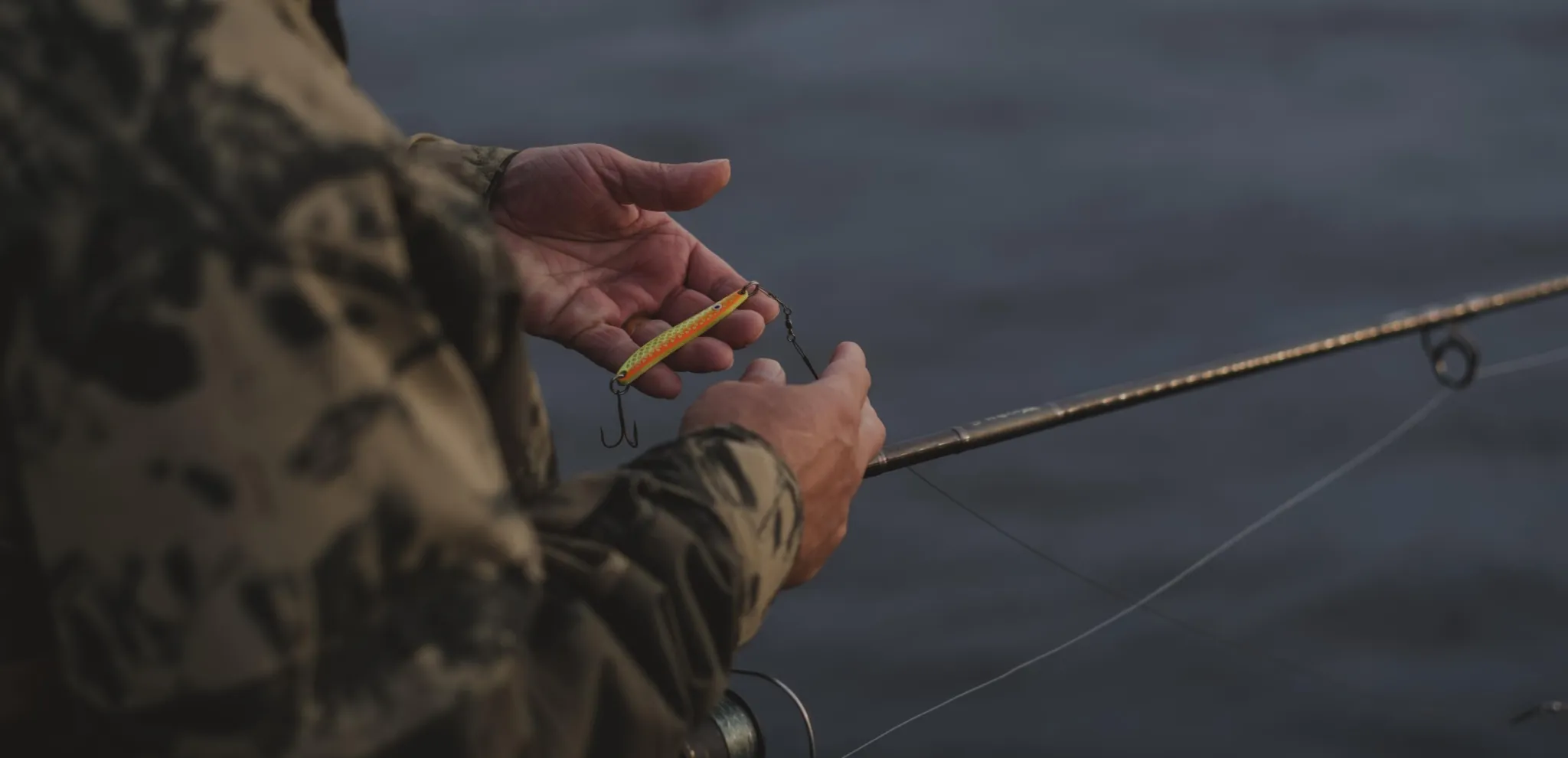 Close up of a man's hands holding a fishingrod and bait