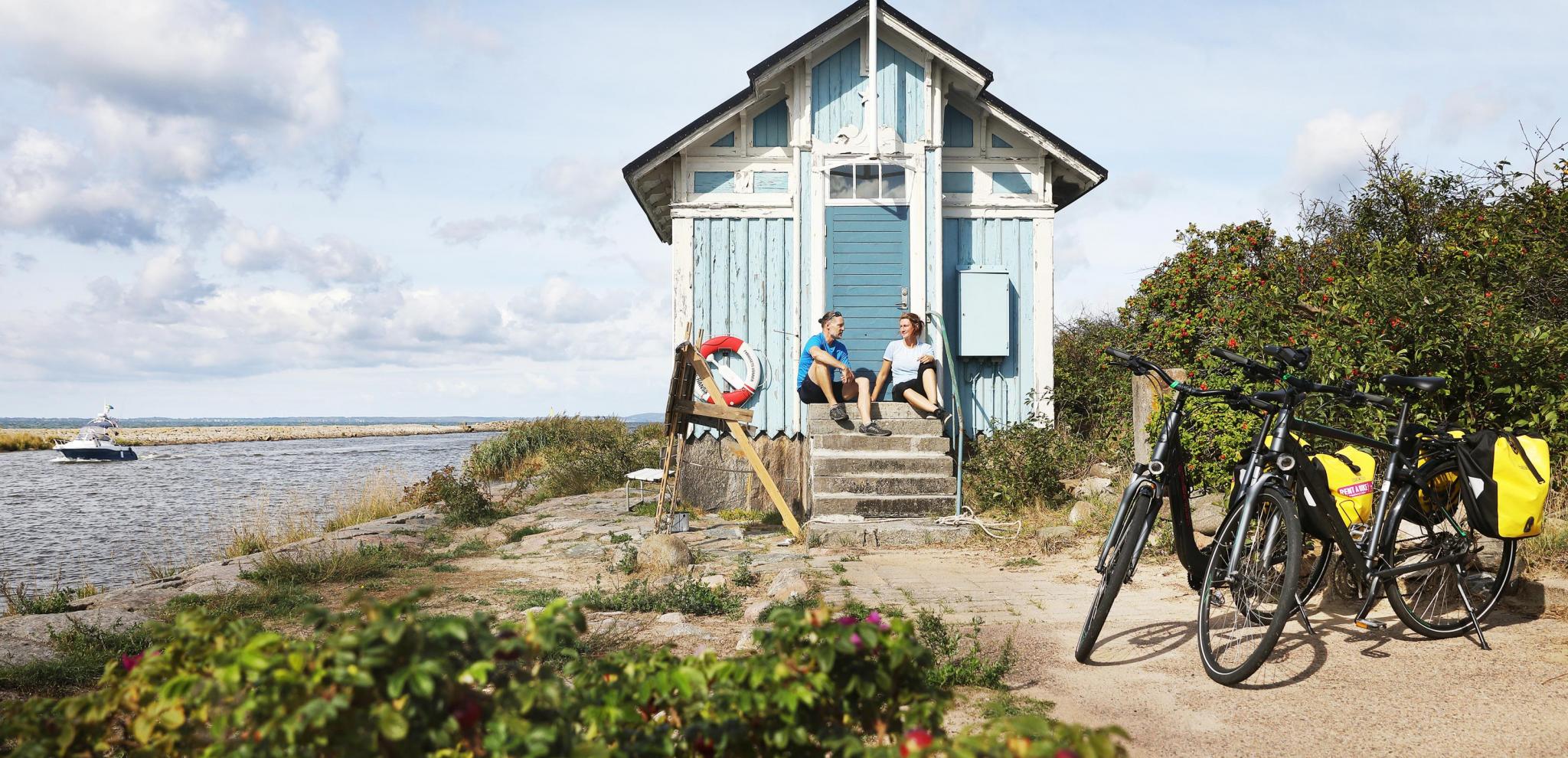 Couple with bicycles having a break by a beach cabin 