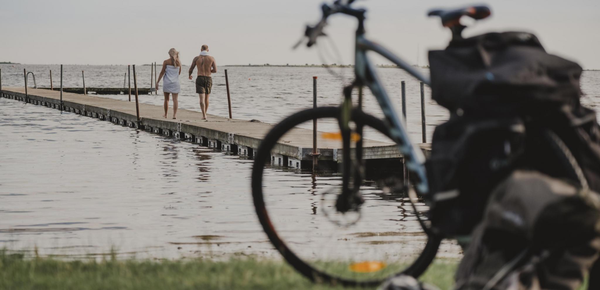 A couple on a pier going for a swim after biking in Skåneleden