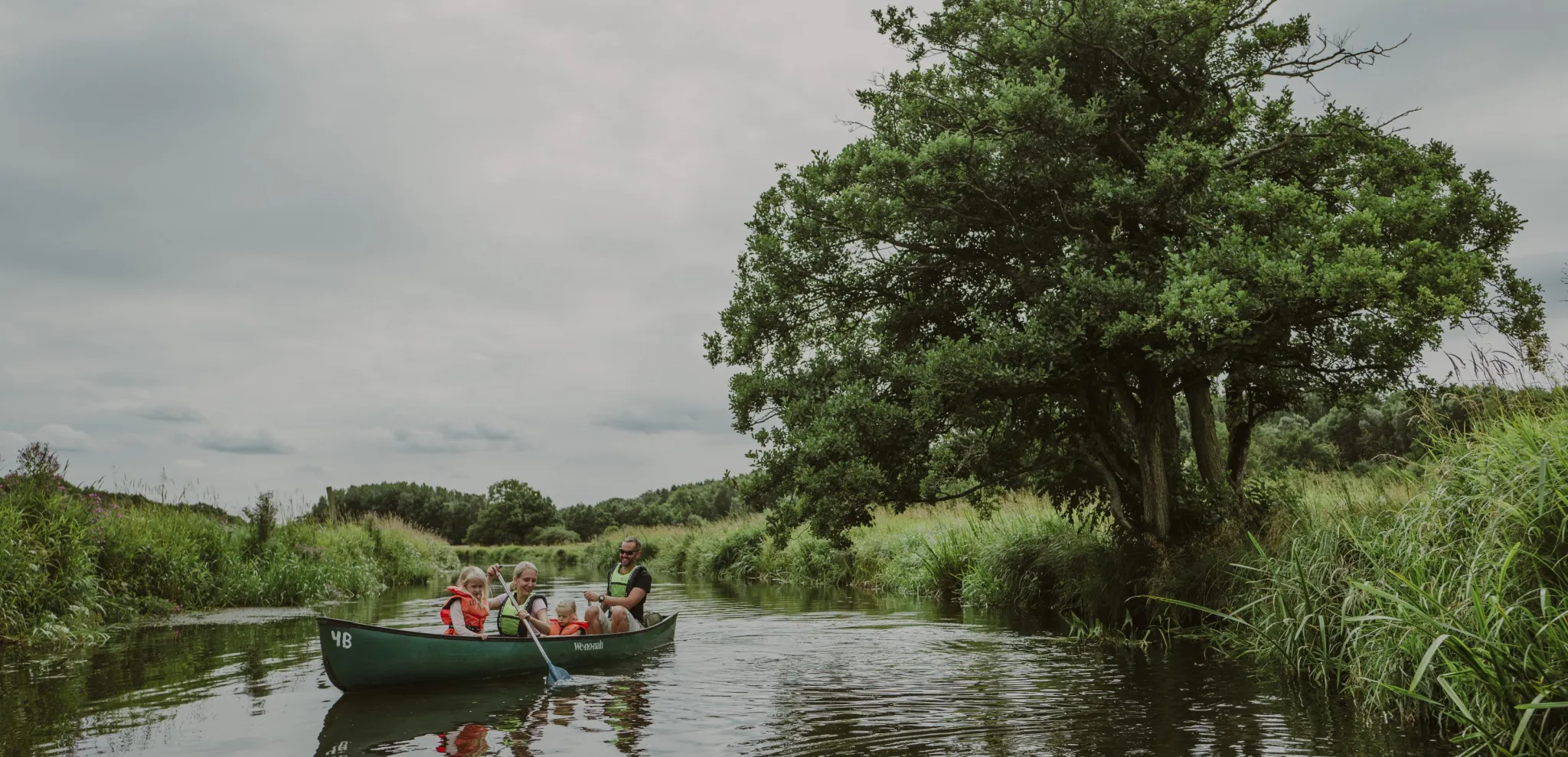 Family canoeing through nature by the Rönne river