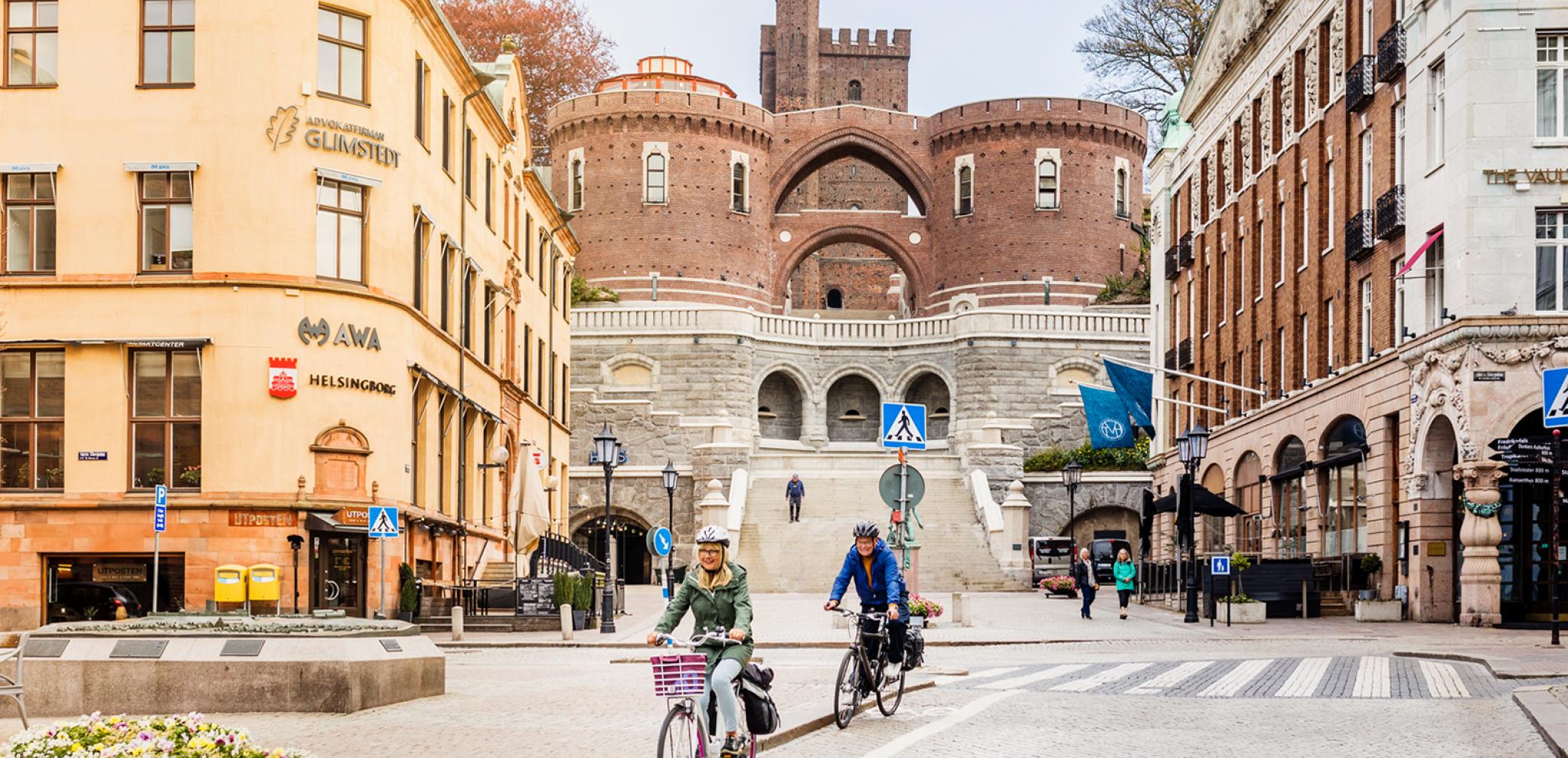 A couple cycling through central Helsingborg with the Terrace Stairs in the background