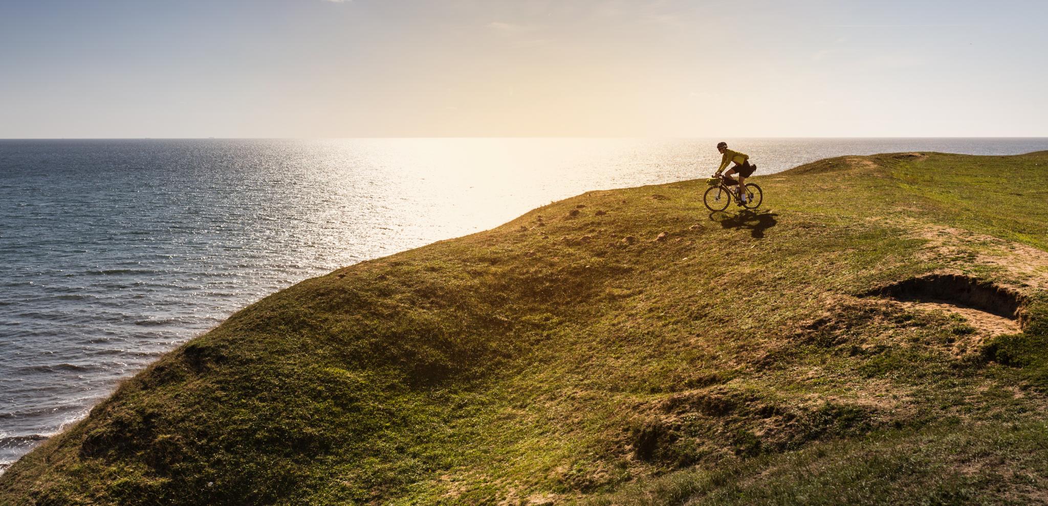 A man is cycling off the track, near the cliffs of Ale's rocks
