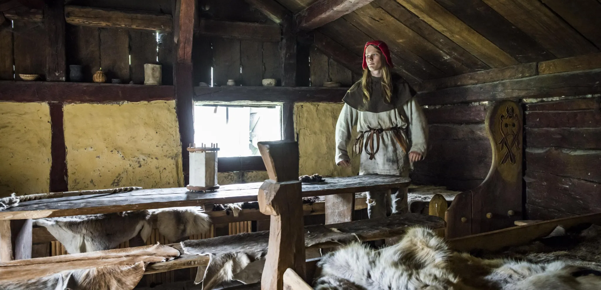 En viking står som står inne i ett vikingahus