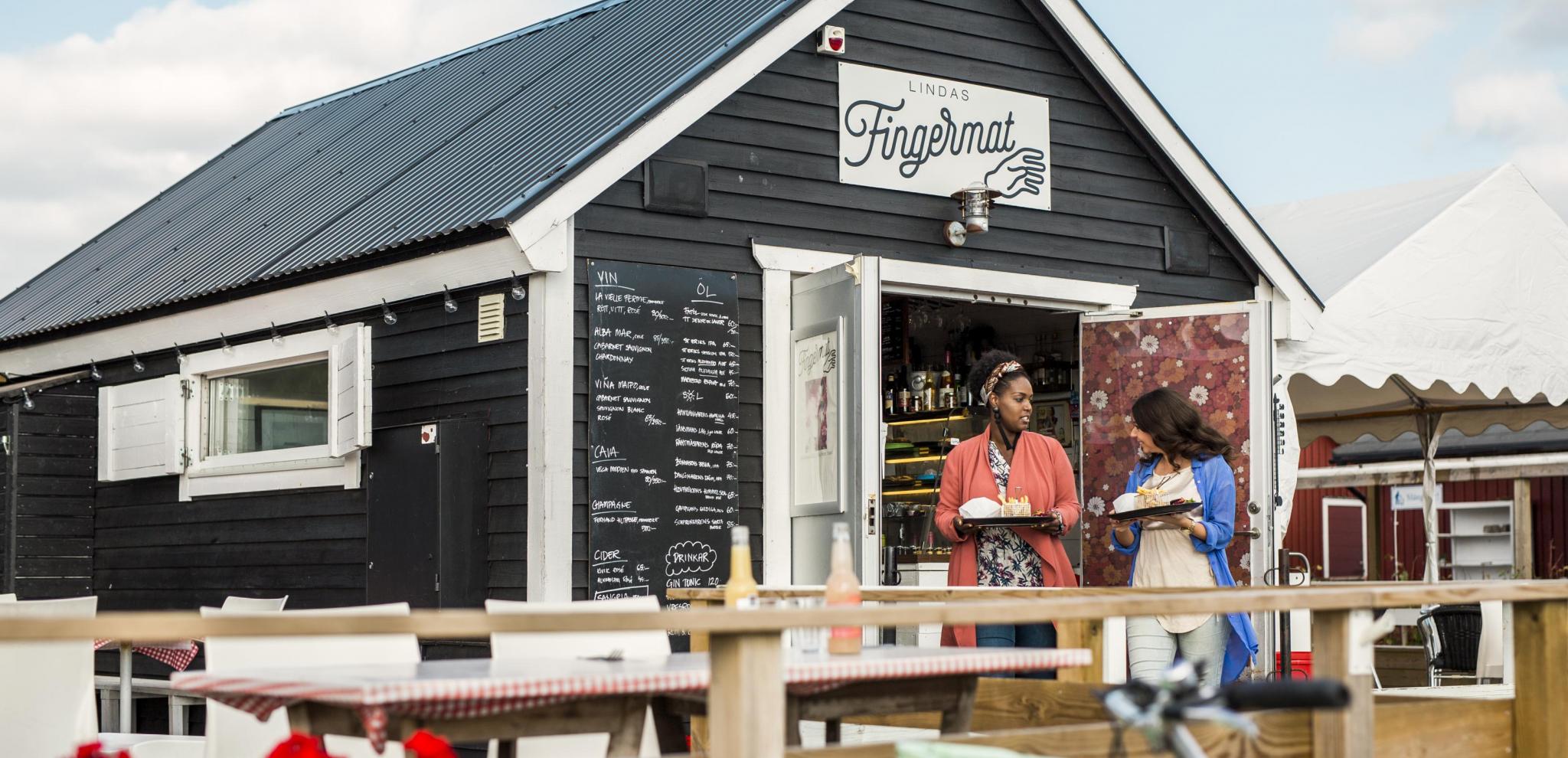 Two women that just bought food from a foodshed called Lindas fingermat.