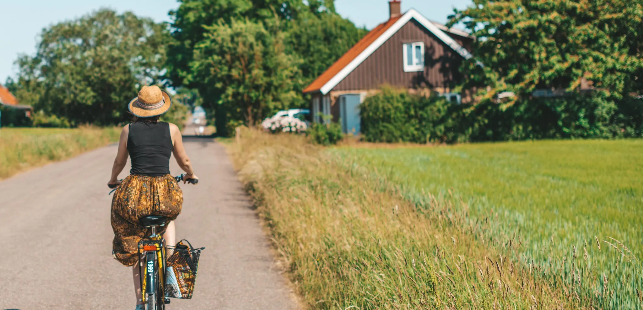 Kvinna som cyklar på en landsväg i Ven en vacker sommardag