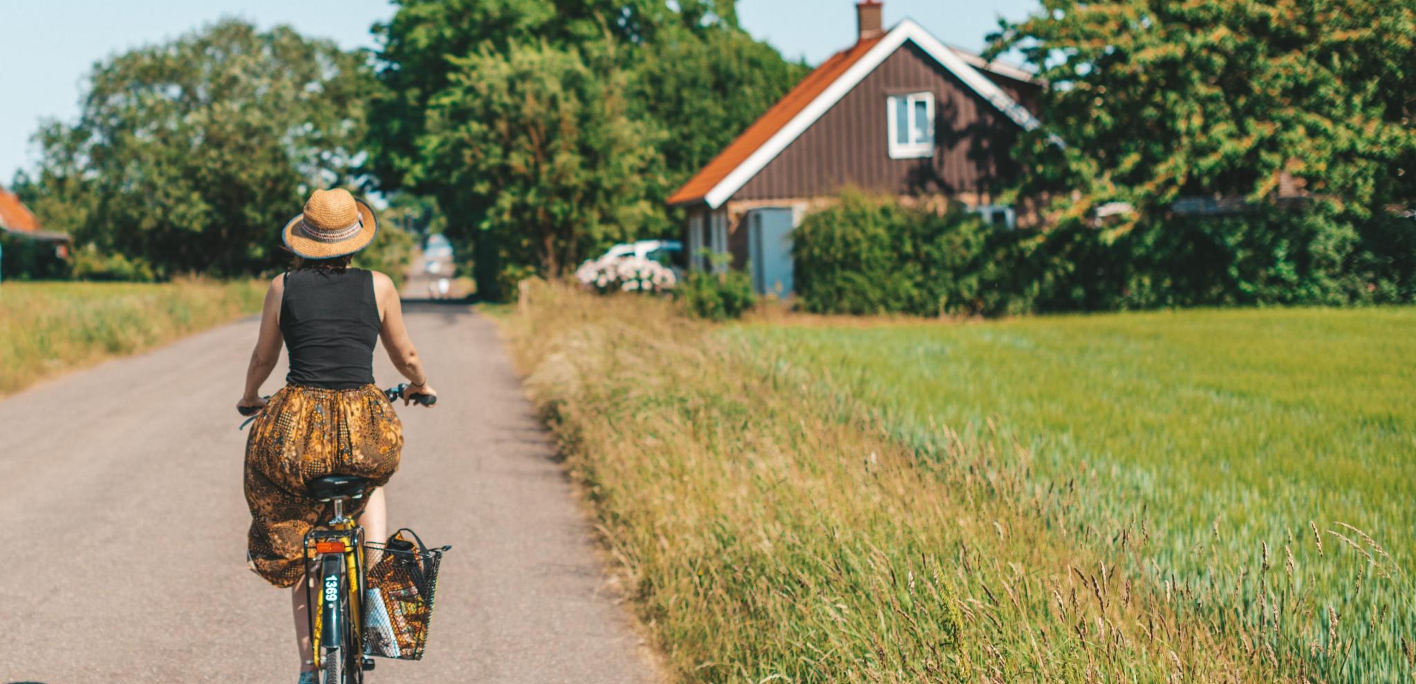 Kvinna som cyklar på en landsväg i Ven en vacker sommardag