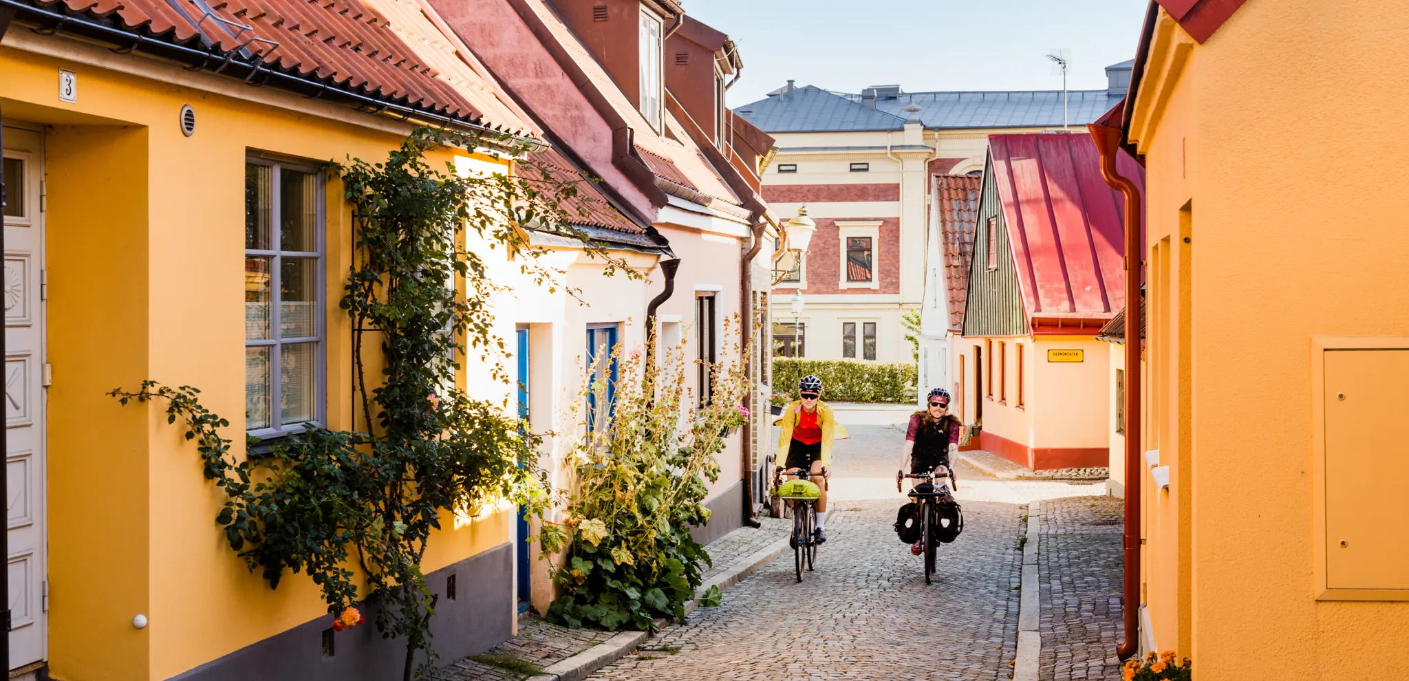  Two cyclists come cycling on a cobbled street among picturesque houses.