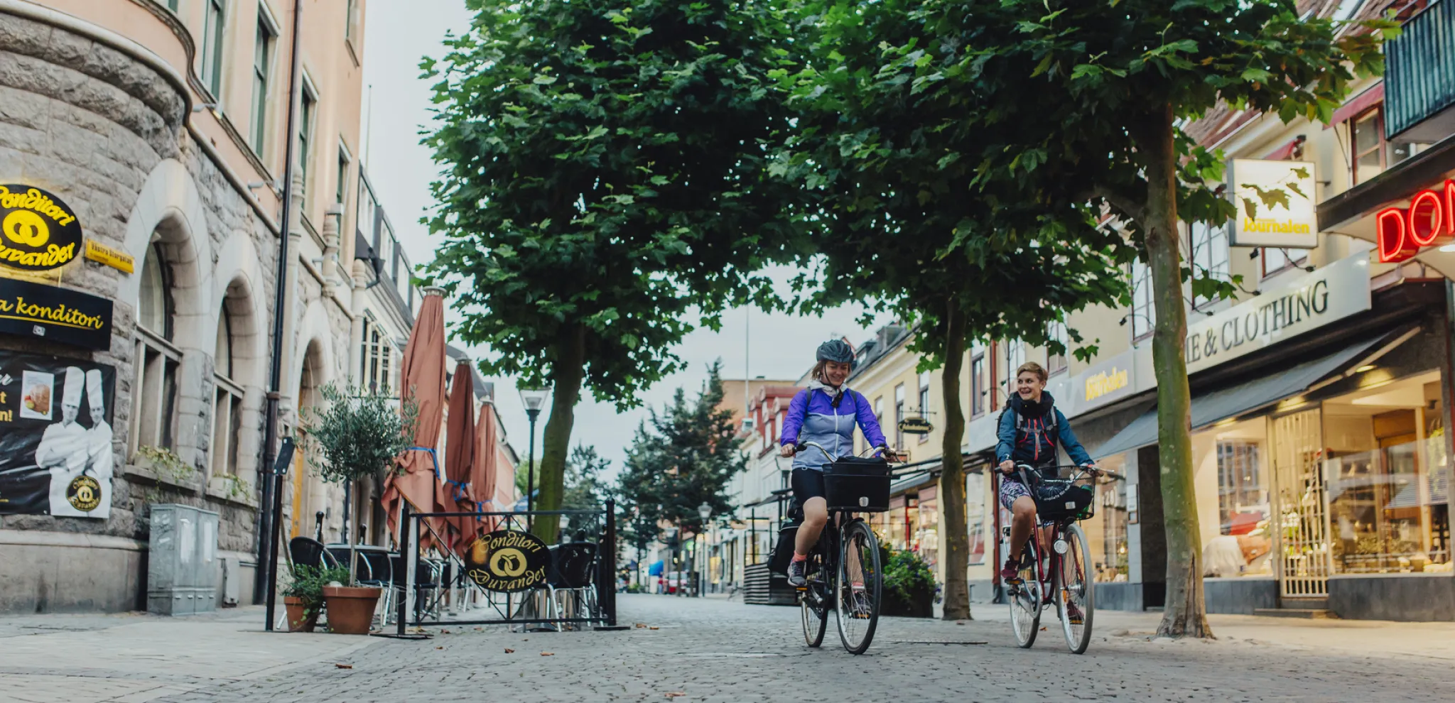 Two women cycling on a shopping street