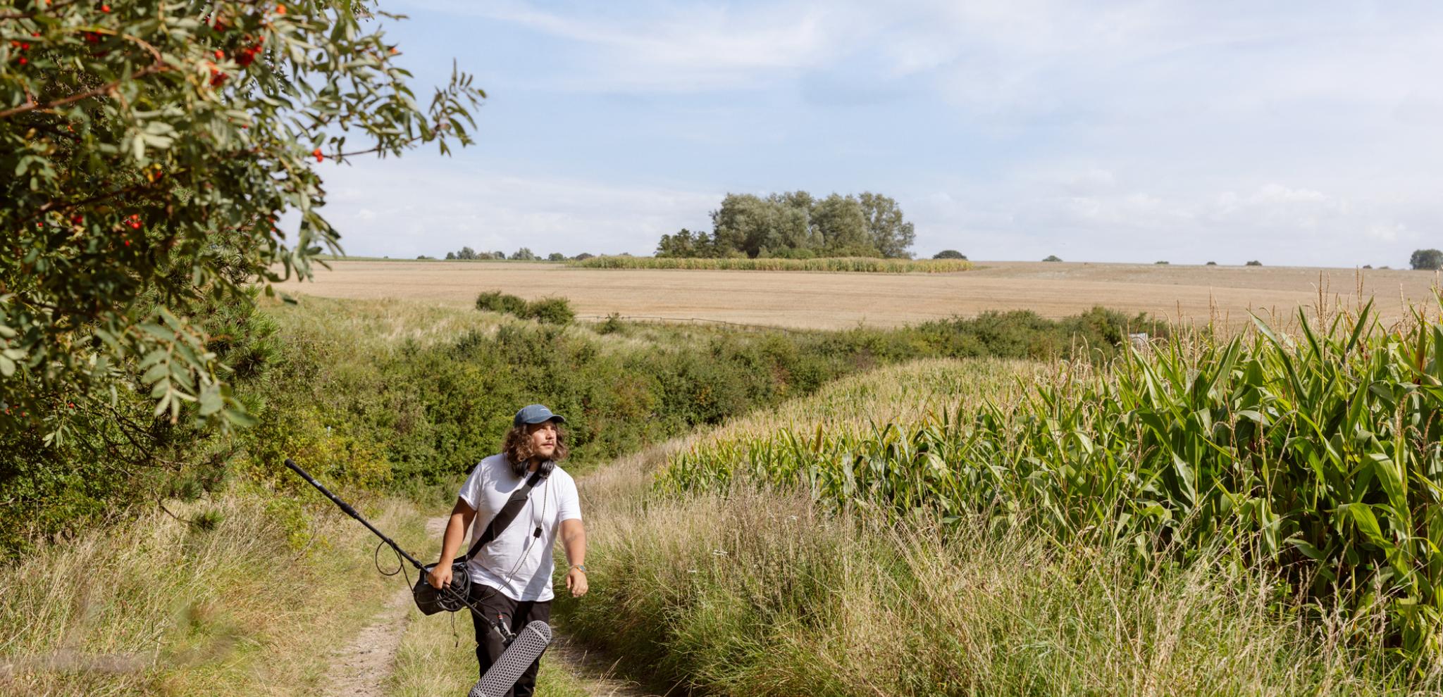 Sound guy walking next to fields on Ven