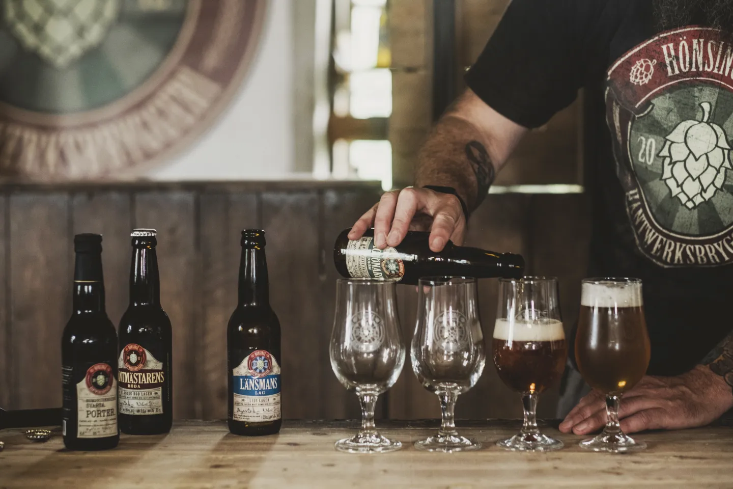 En man häller upp öl i små ölglas på Hönsinge bryggeri