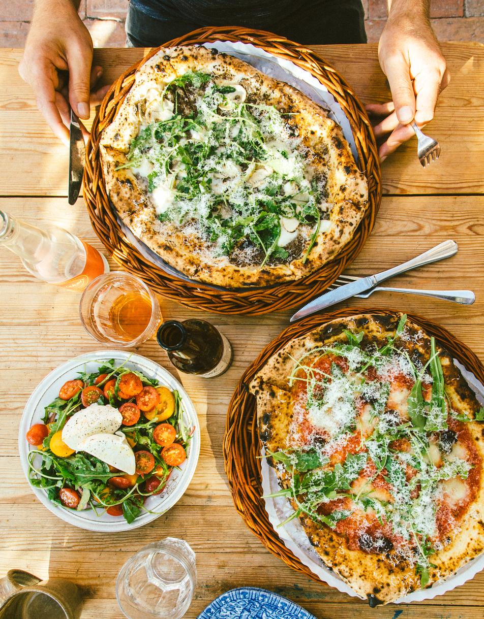 Two pizzas and salad on wooden table 