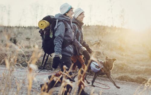 Två personer på vandring med hund