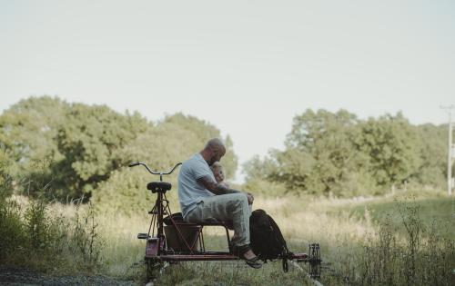 A father and daughter sit on a trolley cycle surrounded by nature
