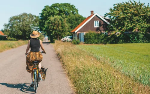 Kvinna som cyklar på en landsväg i Ven en vacker sommardag