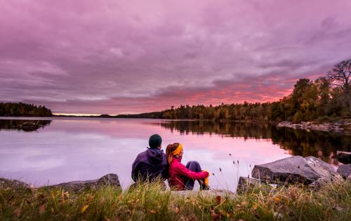 Ett par sitter intill Immeln sjön och tittar på solnedgången
