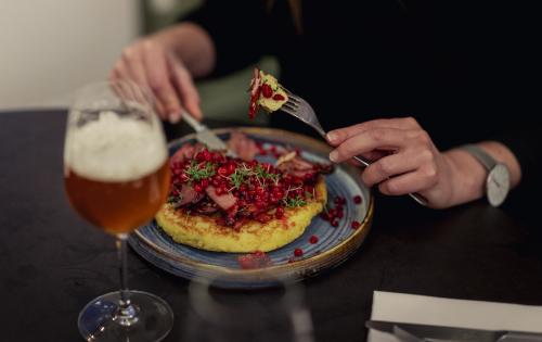 Thick pancake with bacon and lingonberries on top with glass of beer on the side