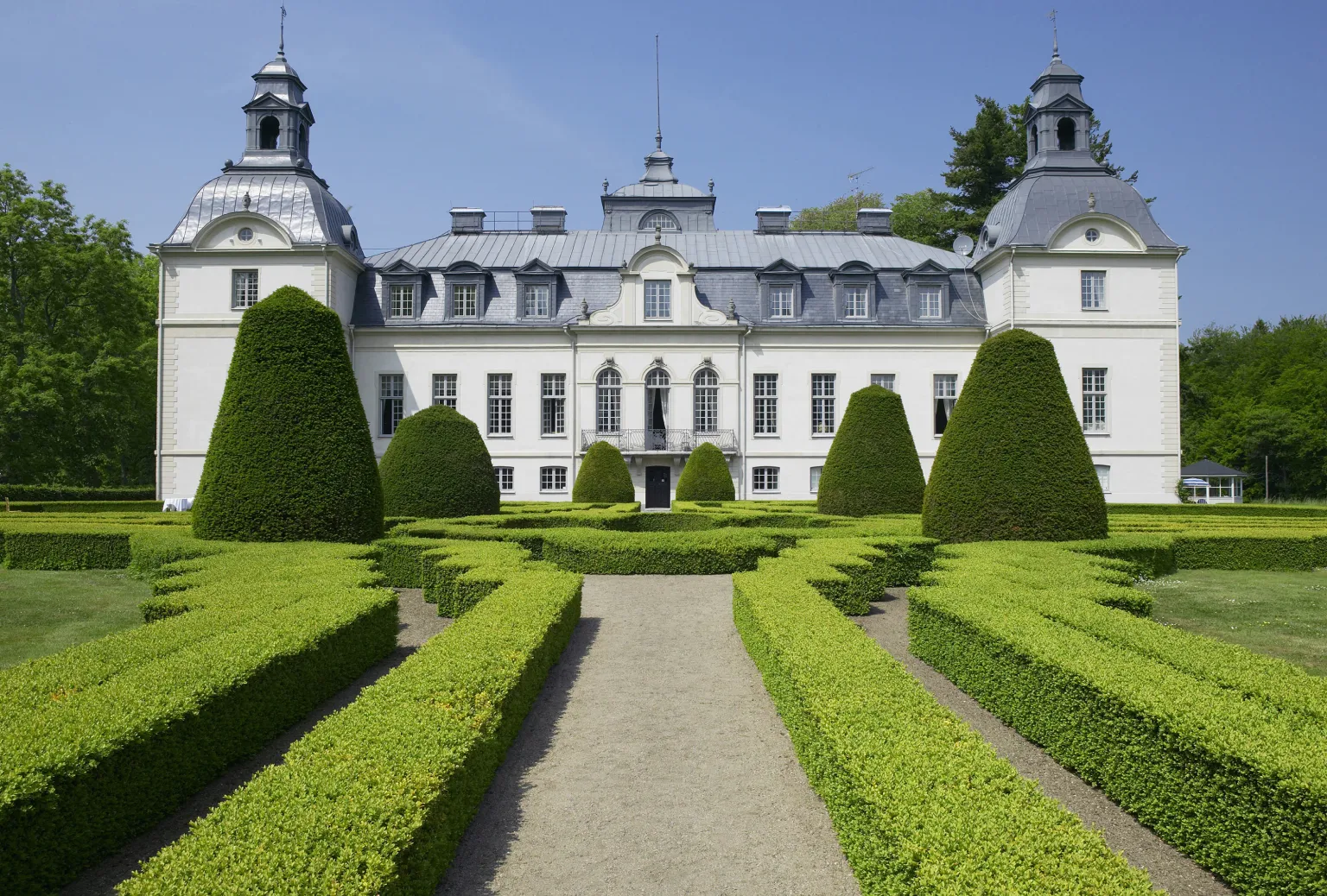 A boxwood garden maze with the fairytale Kronovalls chateaux in the background