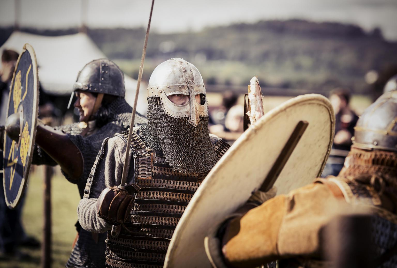 Verkleidete Wikingersoldaten mit Schwertern und Schilden in einem Wikingerdorf.