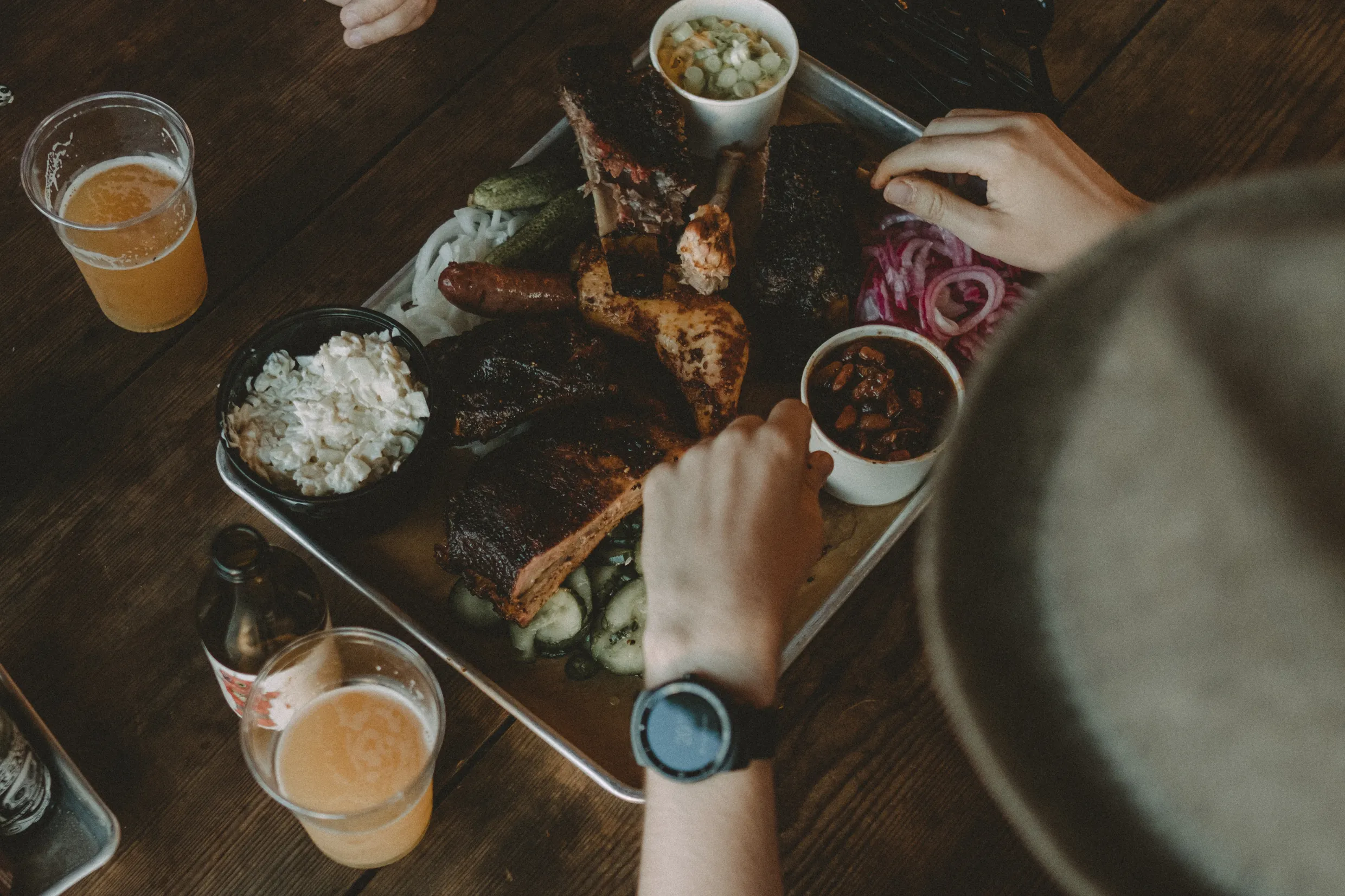BBQ food on steel plate with beer and person eating